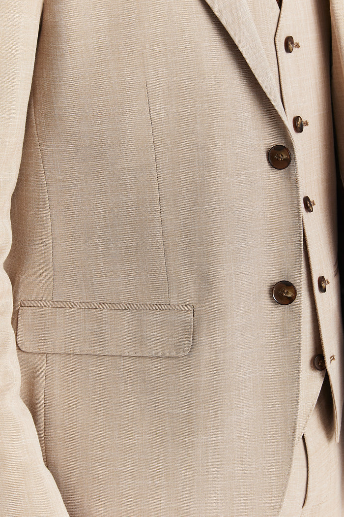 Close-up of the beige blazer highlighting the flap pocket, brown buttons, and smooth textured fabric.