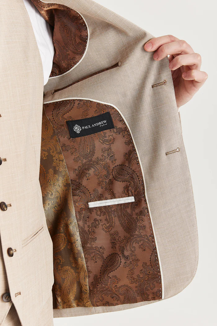 Inside view of the beige suit jacket featuring rich brown paisley lining and Paul Andrew branding.