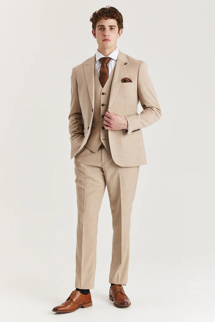 Full front view of a man in a beige three-piece suit paired with brown brogues and a brown tie.