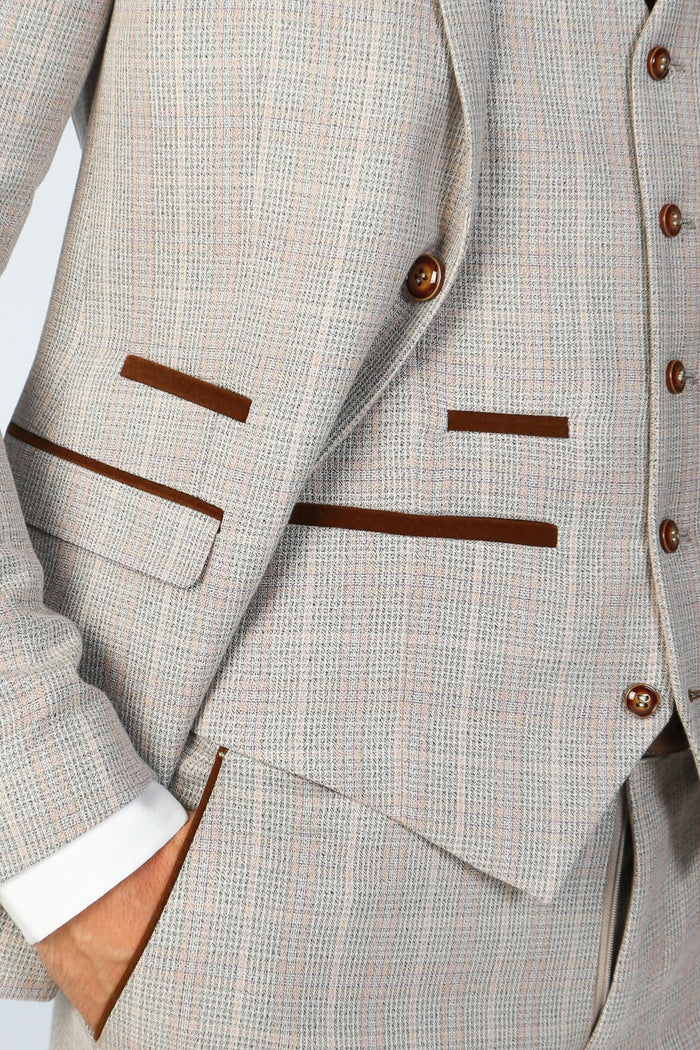 Close-up of beige check blazer and waistcoat showing brown velvet pocket trims and fine texture.