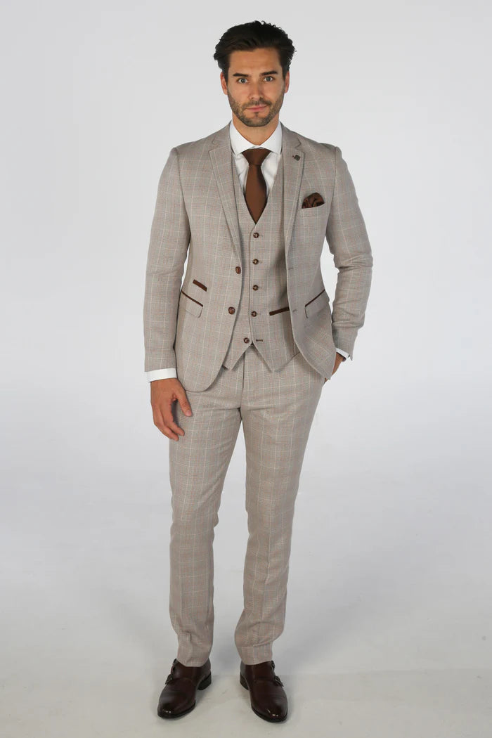 Full view of man in beige check three-piece suit styled with a white shirt, brown tie, and dress shoes.