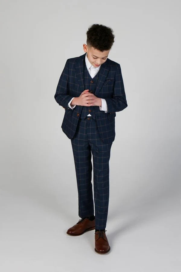 Boy in navy three-piece windowpane suit looking down with hands clasped, showing formal posture in tailored outfit