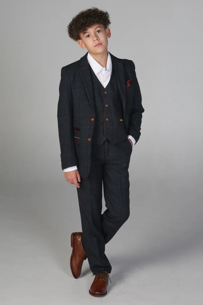 Full body shot of boy in navy check suit with waistcoat and trousers, styled with brown shoes and white shirt.