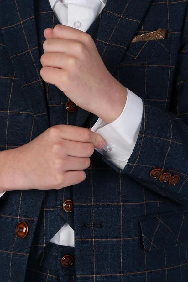 Close-up of boy's hand adjusting white shirt cuff beneath navy windowpane suit with brown buttons.