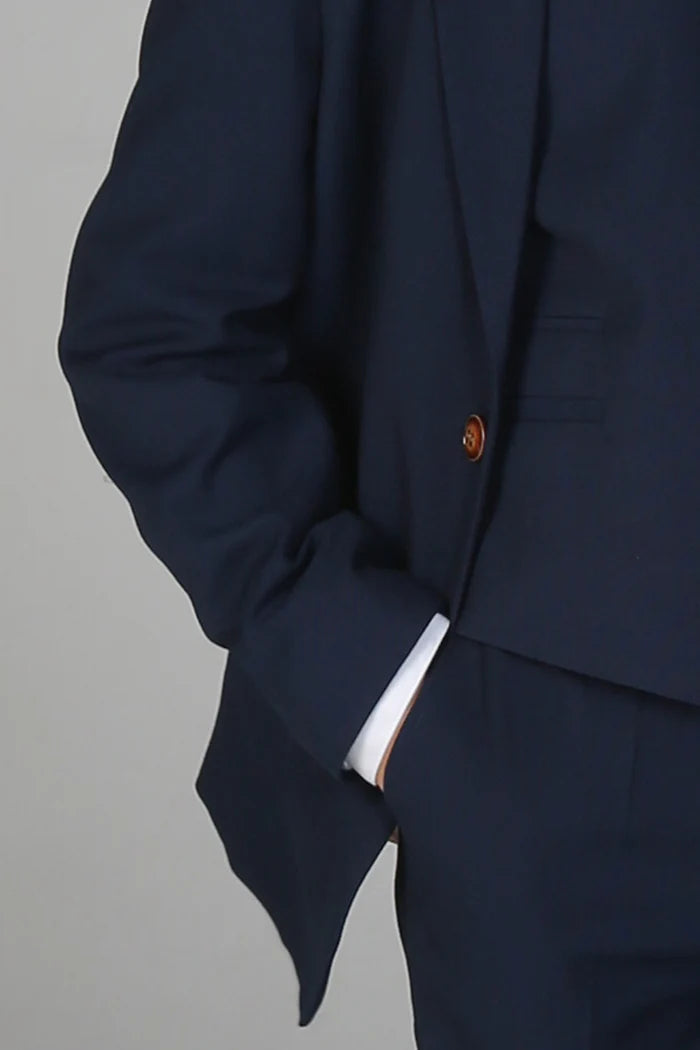 Close-up of navy suit jacket sleeve and brown button accent with visible white shirt cuff.
