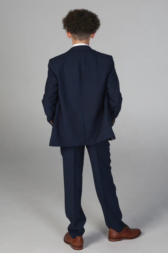 Rear view of boy in classic navy suit jacket and trousers showcasing clean cut and structure.