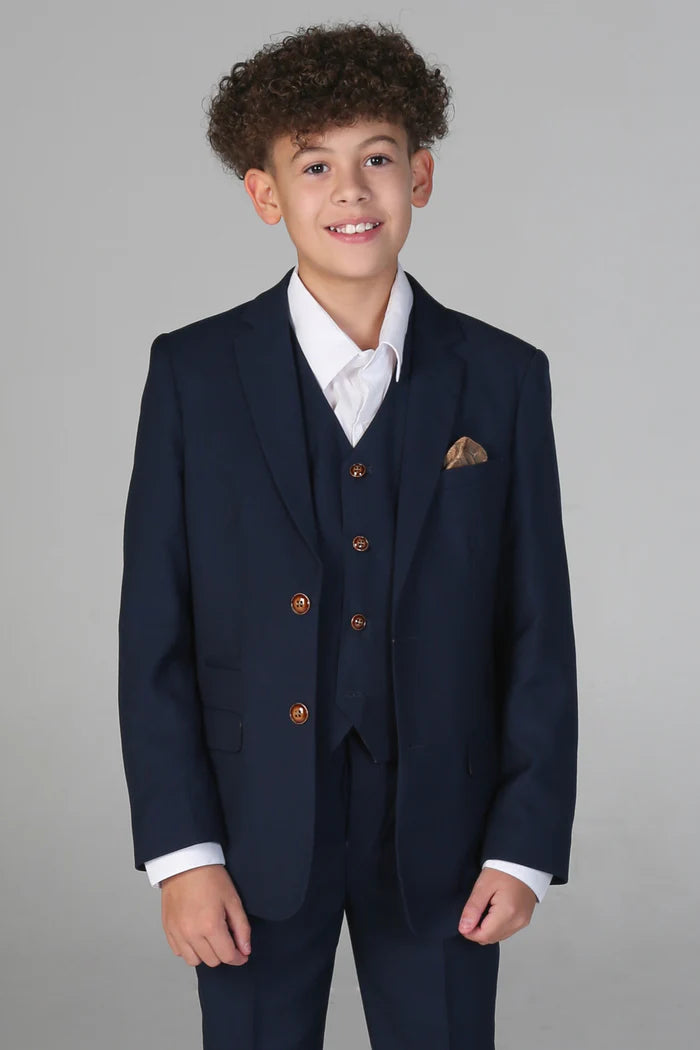 Boy wearing a navy three-piece suit with brown buttons and gold pocket square over a white dress shirt.