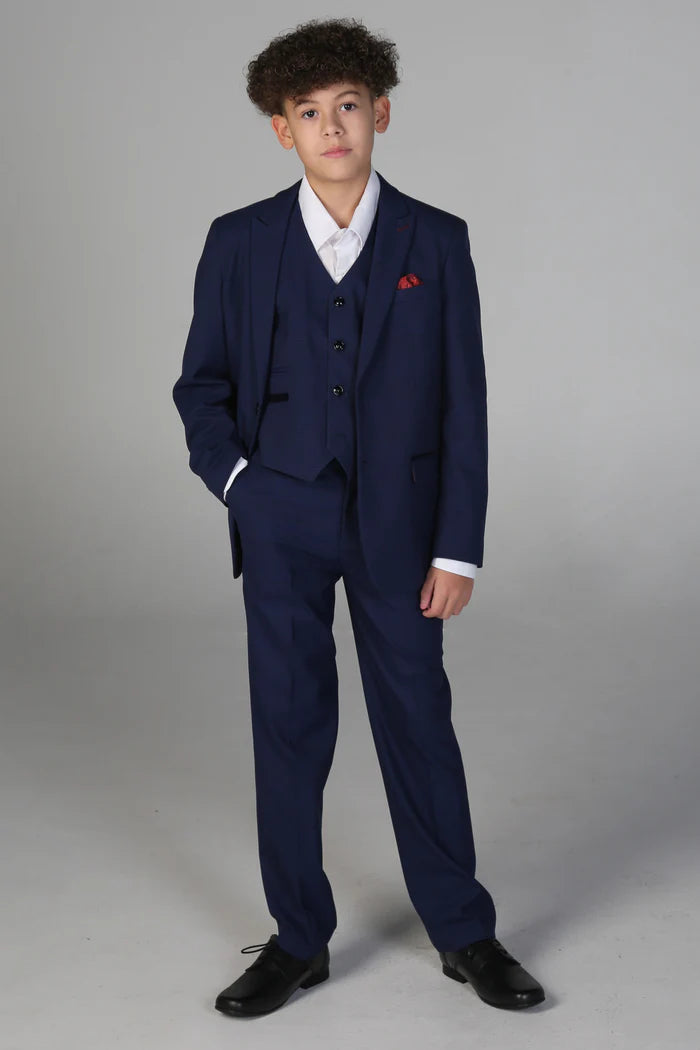Full front view of boy in navy blue three-piece suit with red handkerchief, white shirt, and black shoes.