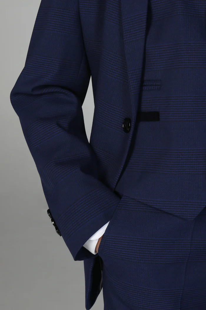 Detail of button and pocket stitching on a navy boys’ suit jacket with subtle check pattern.