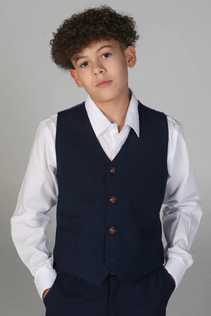 Boy wearing fitted navy waistcoat with brown buttons and matching trousers over a white shirt.