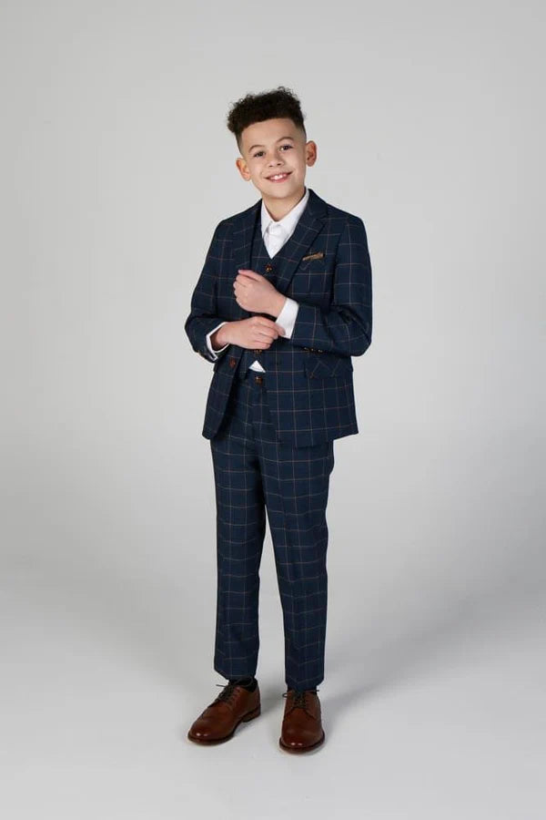 Full-length view of boy in navy formal windowpane suit with arms crossed, paired with white shirt and brown oxford shoes.