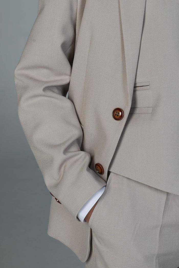 Close-up of stone suit jacket fabric with brown button detailing and fine weave texture.