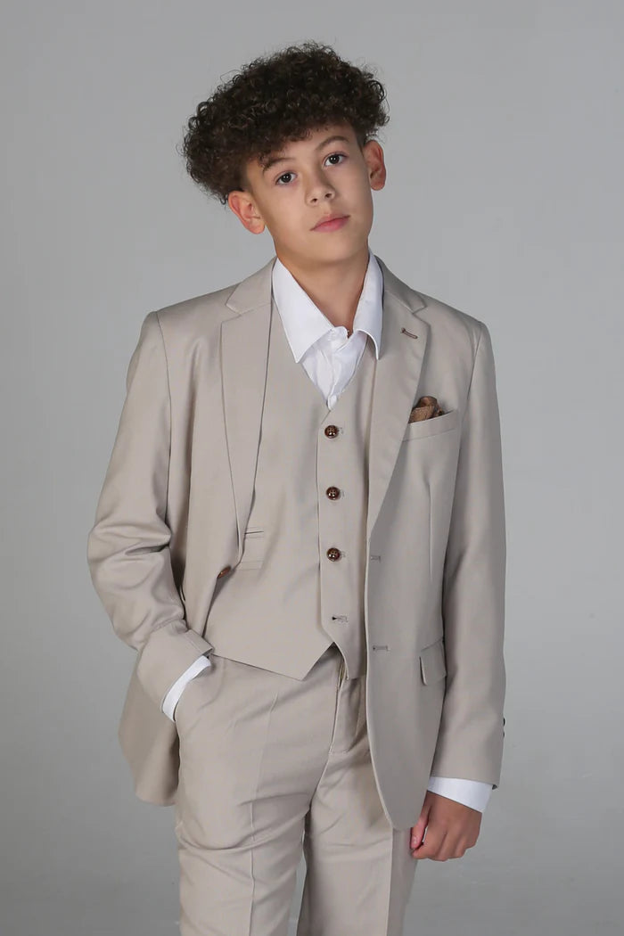 Boy wearing a stone-colored three-piece suit with jacket, waistcoat, and trousers, styled with a white shirt and brown buttons.