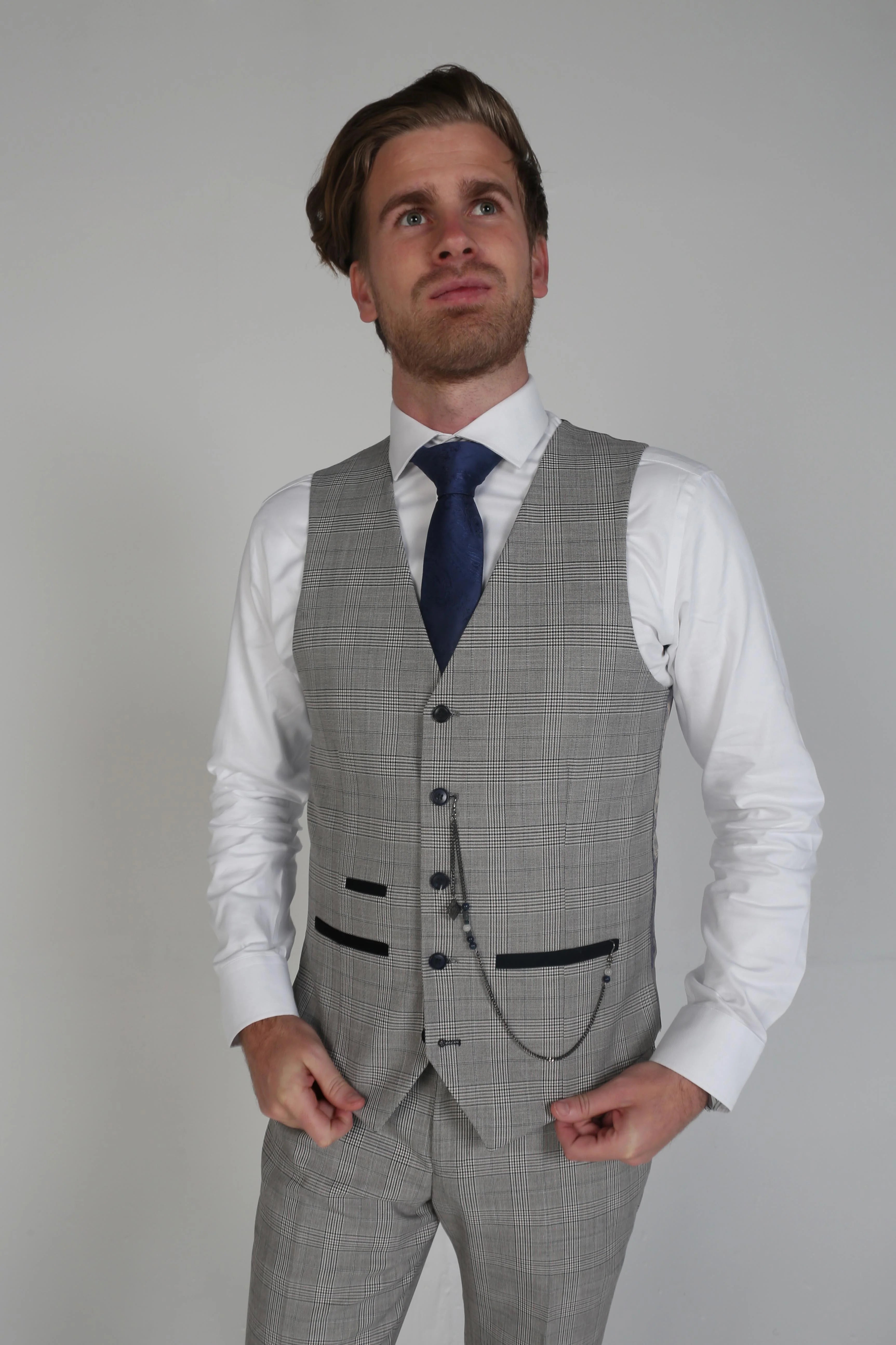 Man wearing a Hugo grey checkered waistcoat and trousers with a white dress shirt and blue tie.