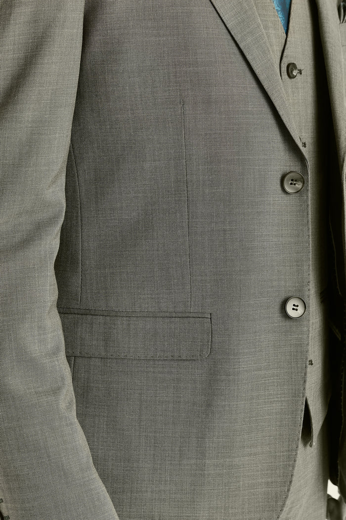 Close-up detail of the sage green blazer’s buttons and pockets.