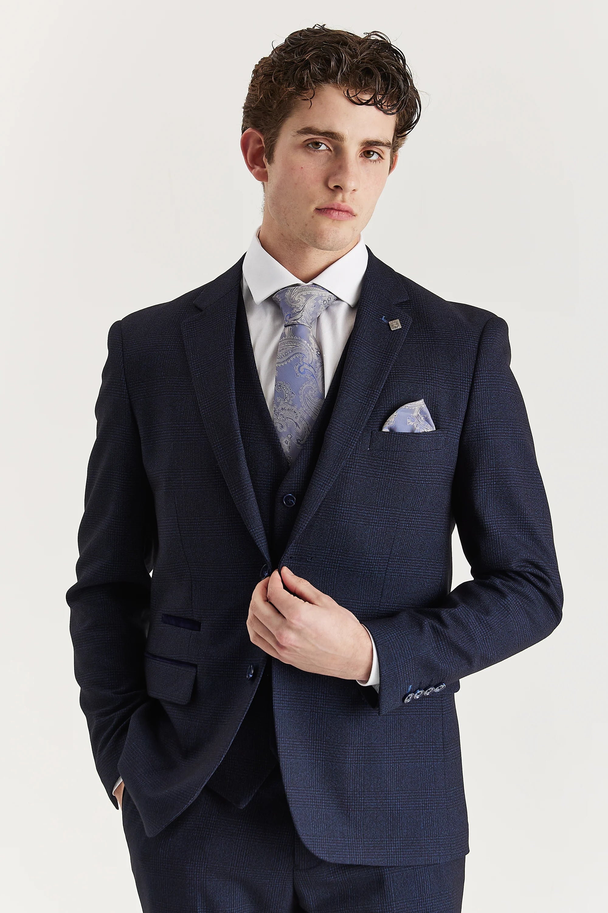 Close-up of a navy check three-piece suit styled with a silver paisley tie and pocket square.