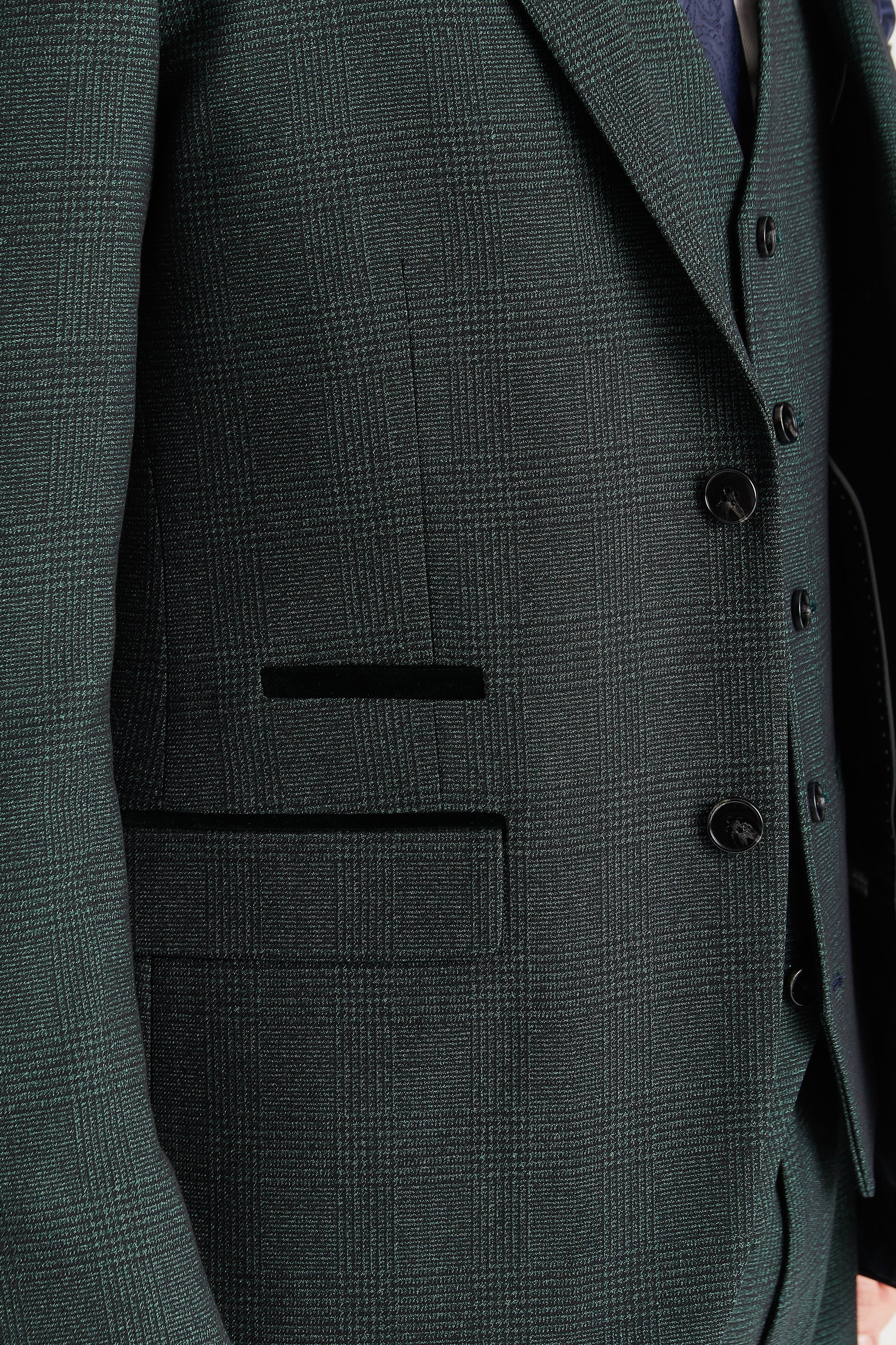 Close-up view of the olive glen check blazer showing the woven check pattern, front flap pocket, dark trim detail above the pocket and dark black buttons.