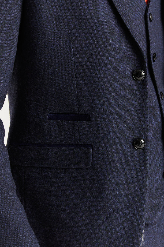 Close-up of Oscar navy tweed suit jacket pocket and button detail highlighting fabric texture and dark trim.
