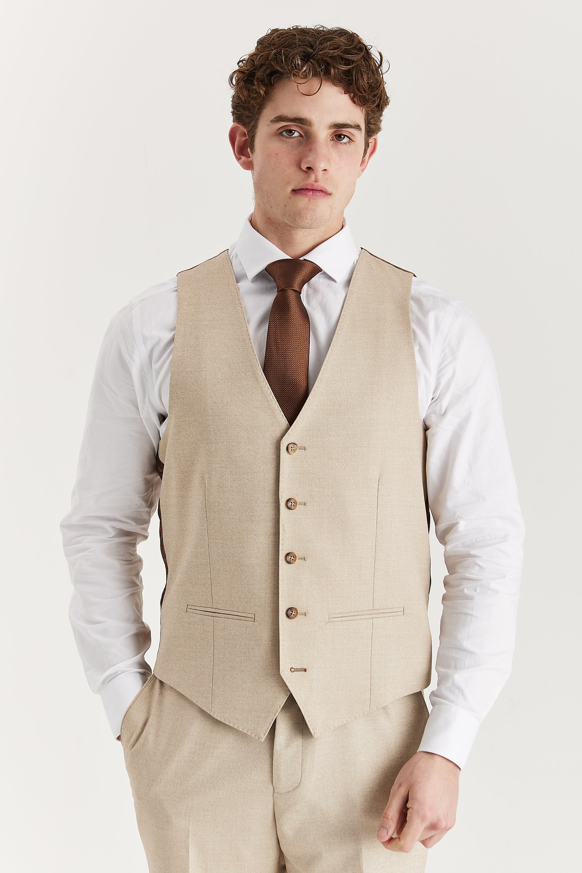 Front view of the beige waistcoat, worn with matching trousers, a white shirt and a brown tie.