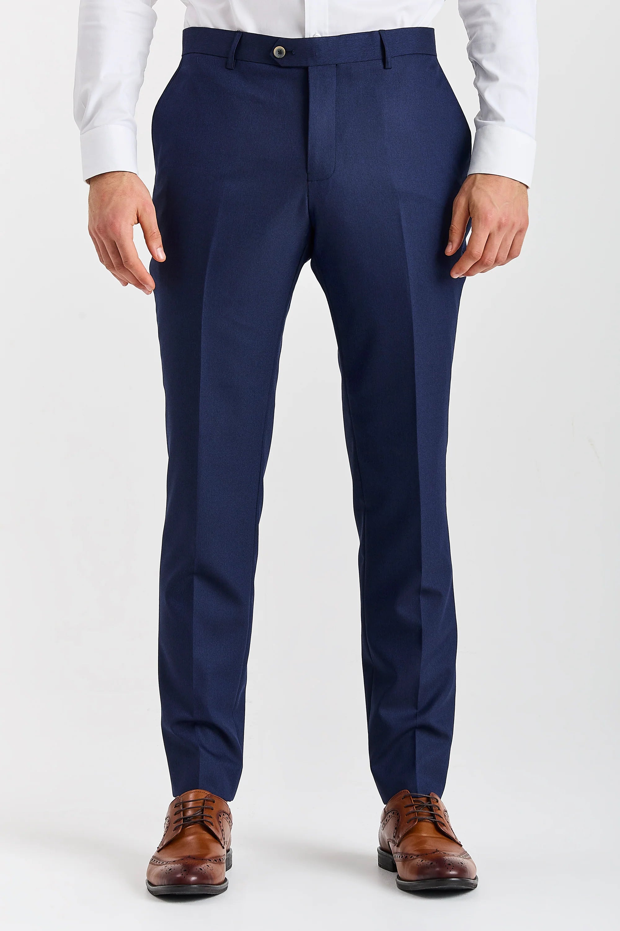 Men’s navy trousers shown from the front, worn with a white shirt and brown brogues.