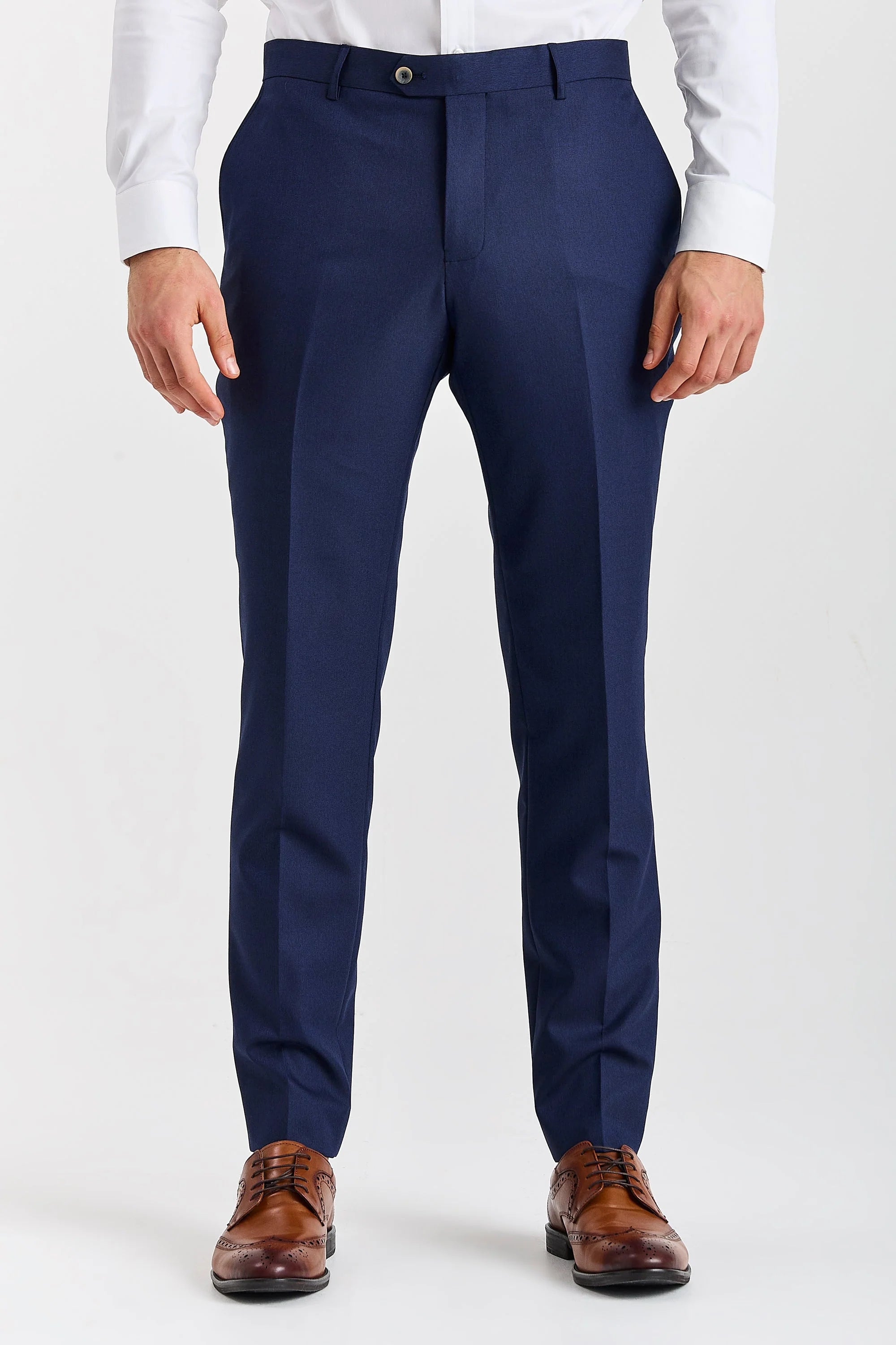 Close-up front view of tailored men's navy suit trousers, ending in brown leather brogue shoes.