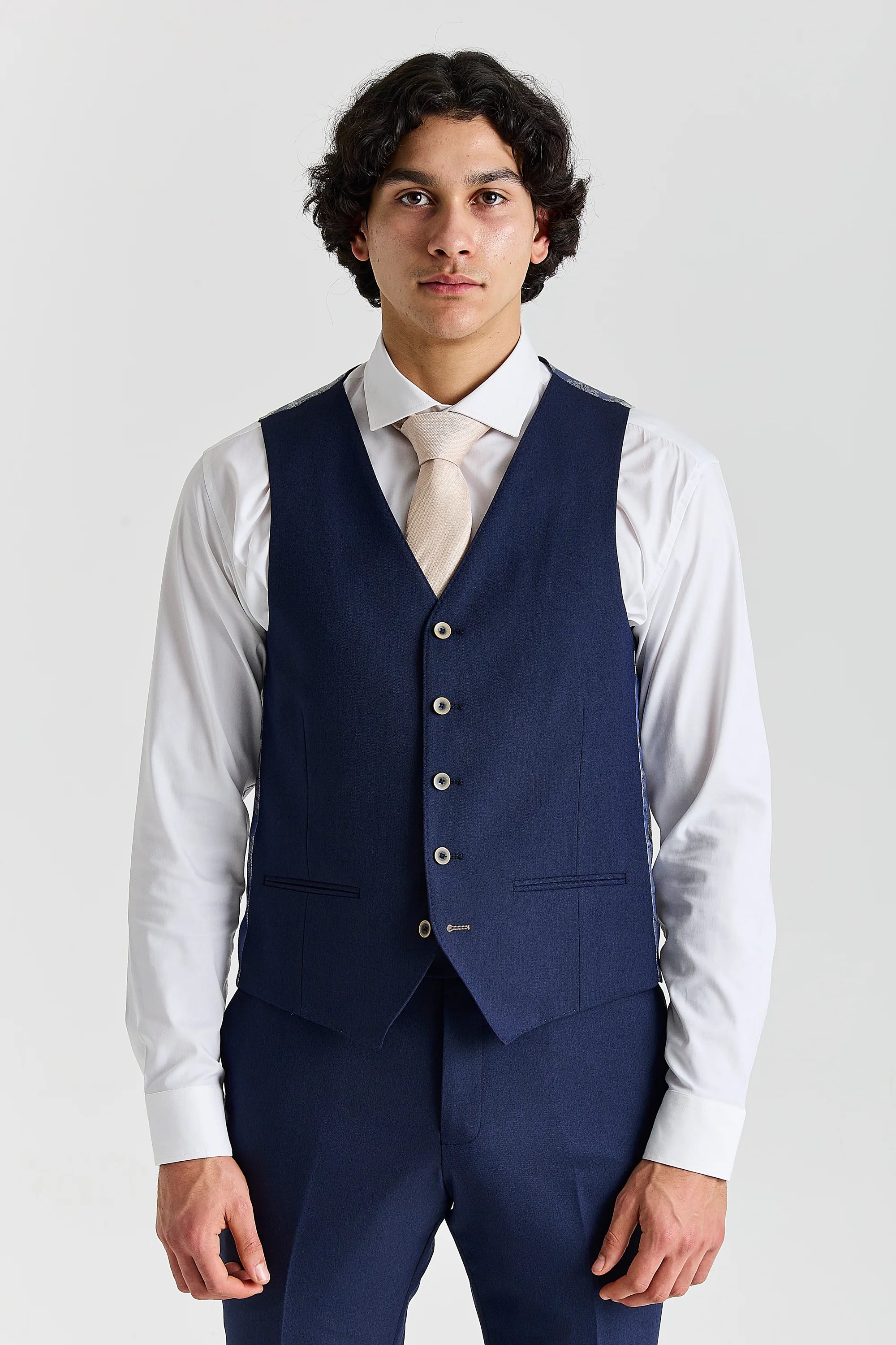 Front view of the navy waistcoat, worn with matching trousers, a white shirt and a cream tie.