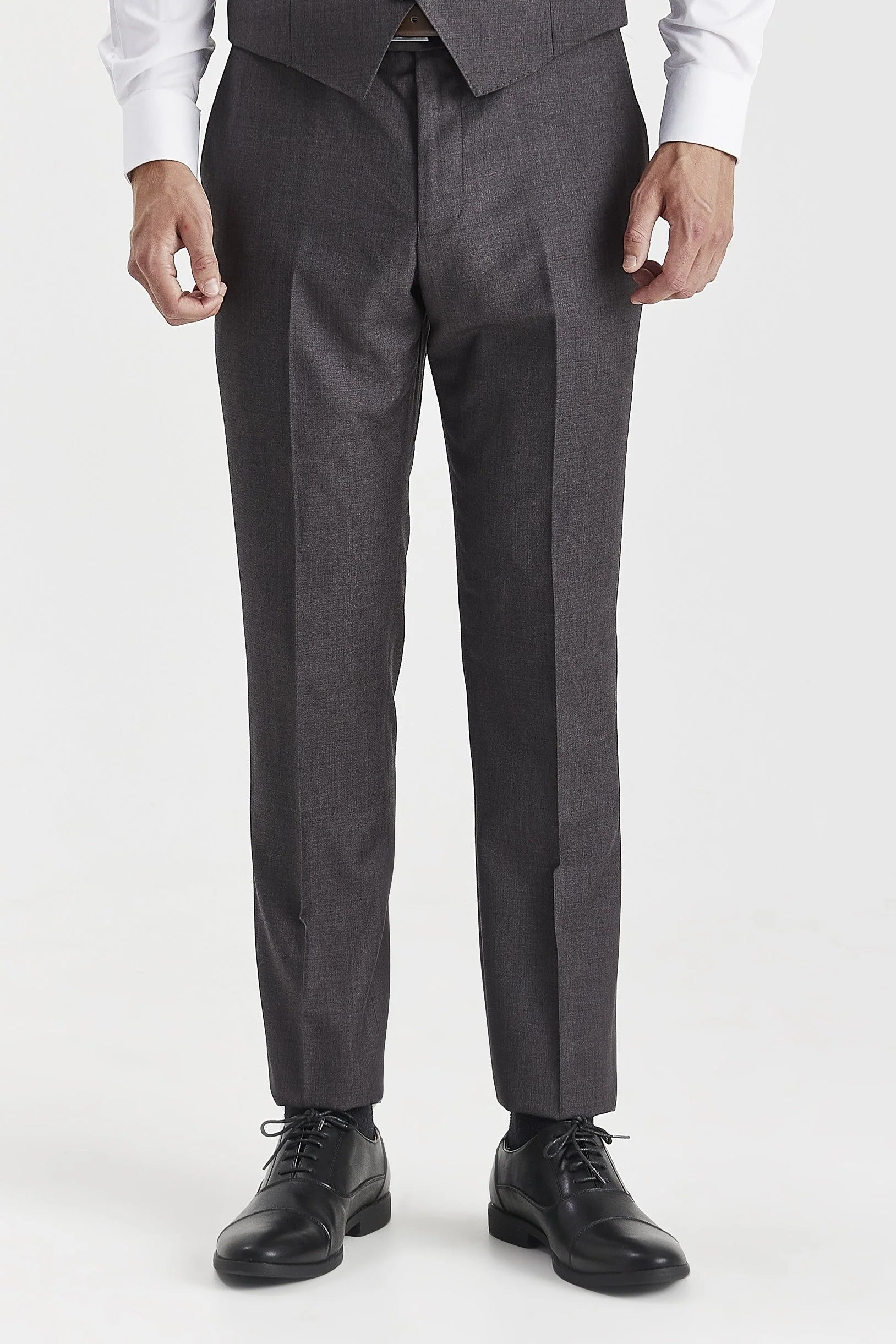 Close-up front view of tailored men's charcoal grey suit trousers and matching waistcoat, wearing black leather dress shoes.