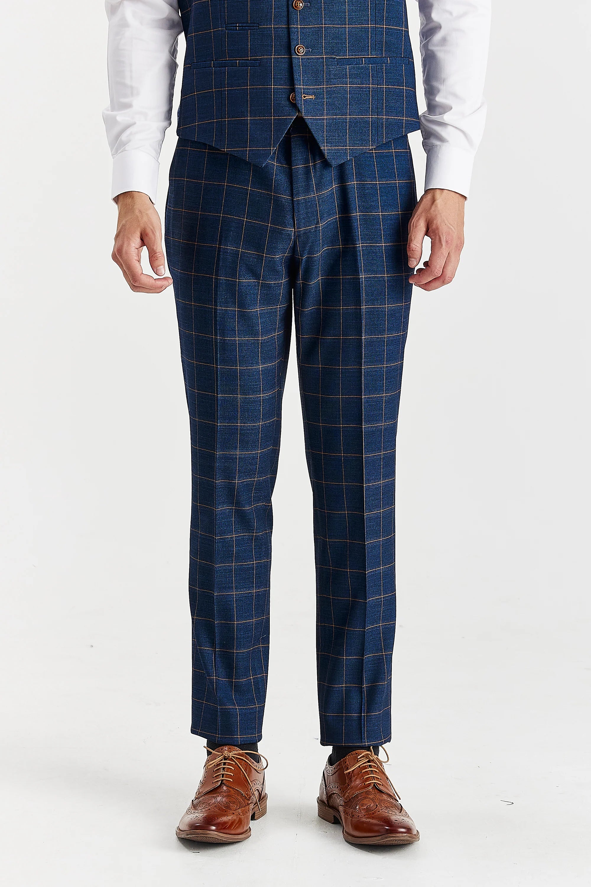 Close-up front view of tailored navy suit trousers with brown windowpane checks and a partially visible matching waistcoat, ending in brown leather brogue shoes