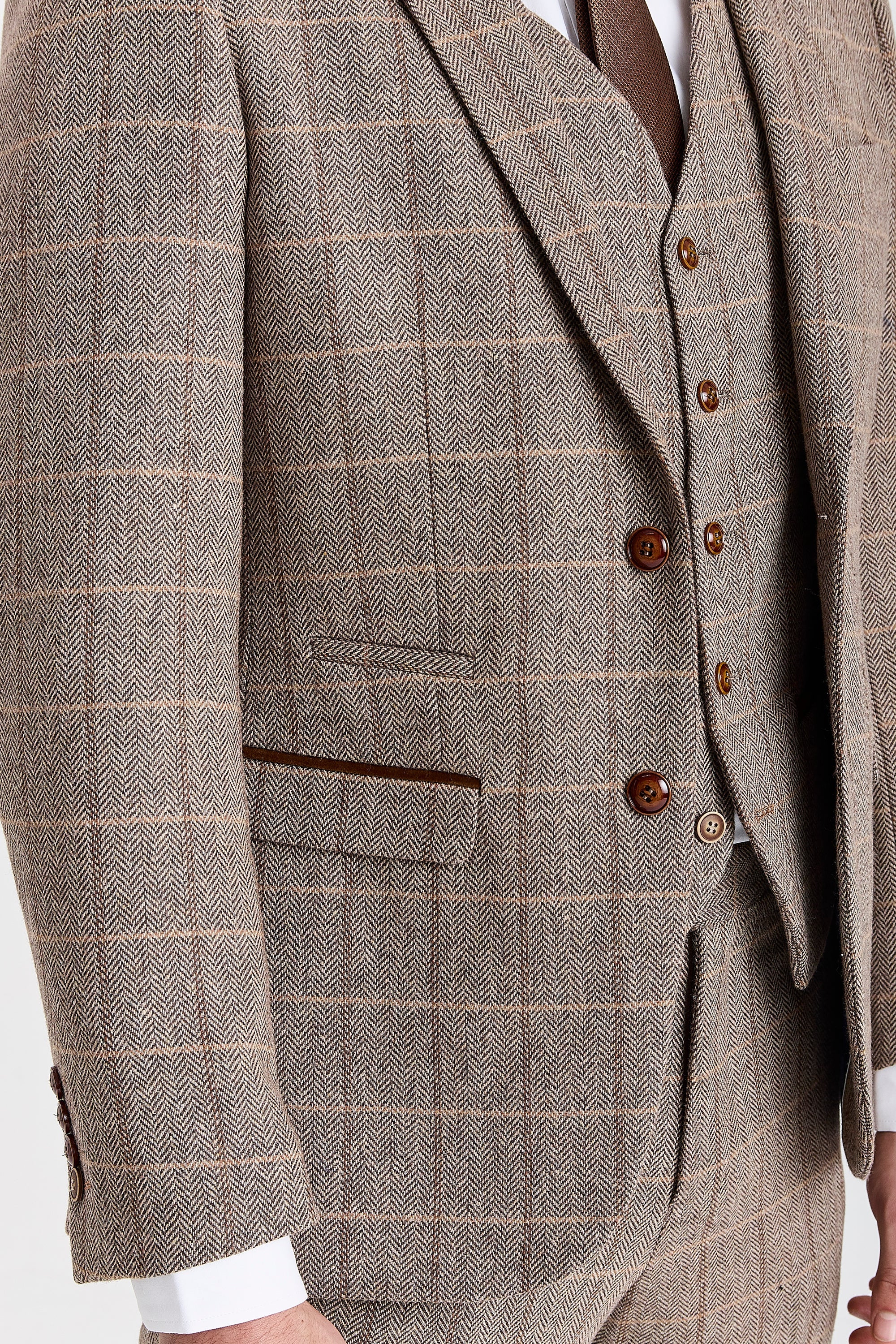 Close-up detail of a Harris brown herringbone tweed check suit jacket and waistcoat with brown buttons and suede pocket trims.