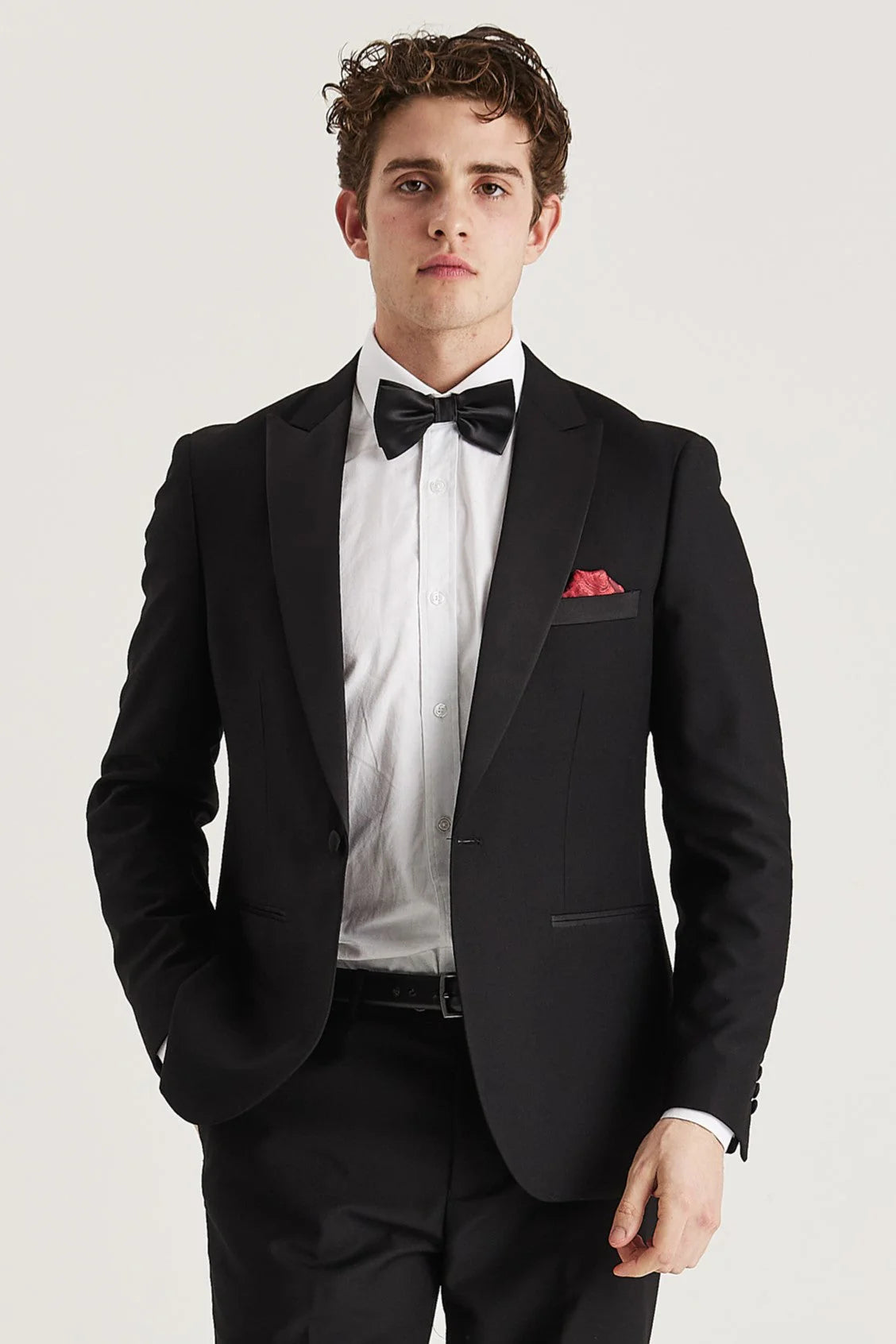 Knee-up front view of a man wearing the blazer from the Harry Black Men's Two Piece Tuxedo , styled with a crisp white shirt, a black bow tie, and a red pocket square.