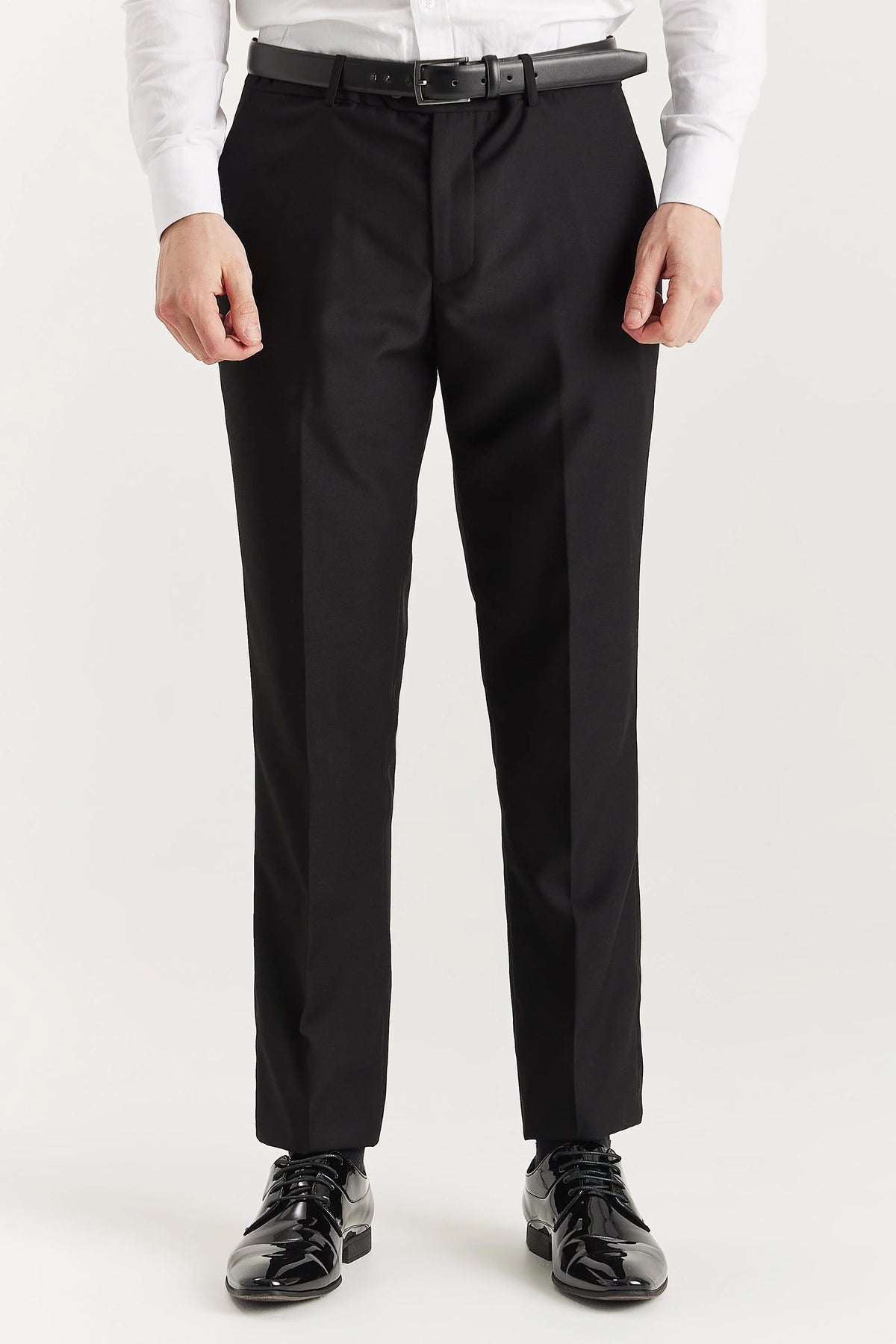 Black dress pants worn by a person on a white background