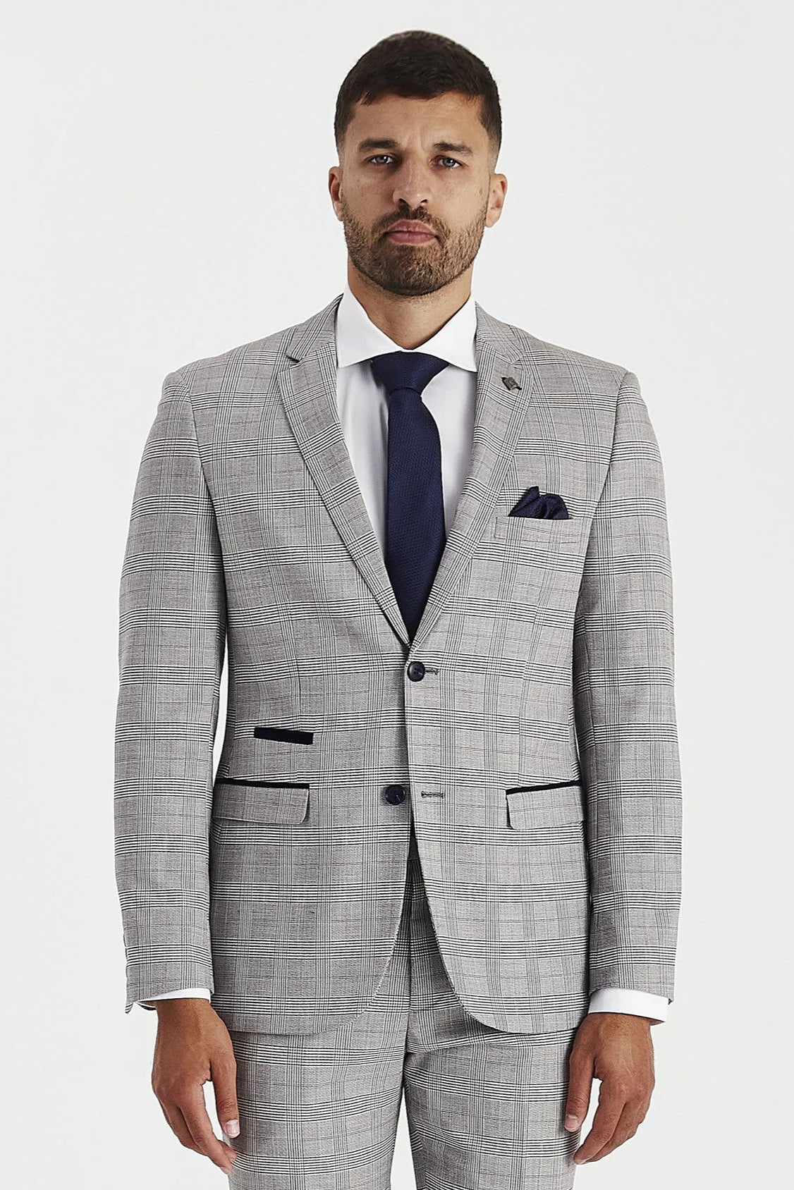 knee-up view of a men's grey windowpane check suit blazer with navy trimmings, a white shirt, and a navy tie.