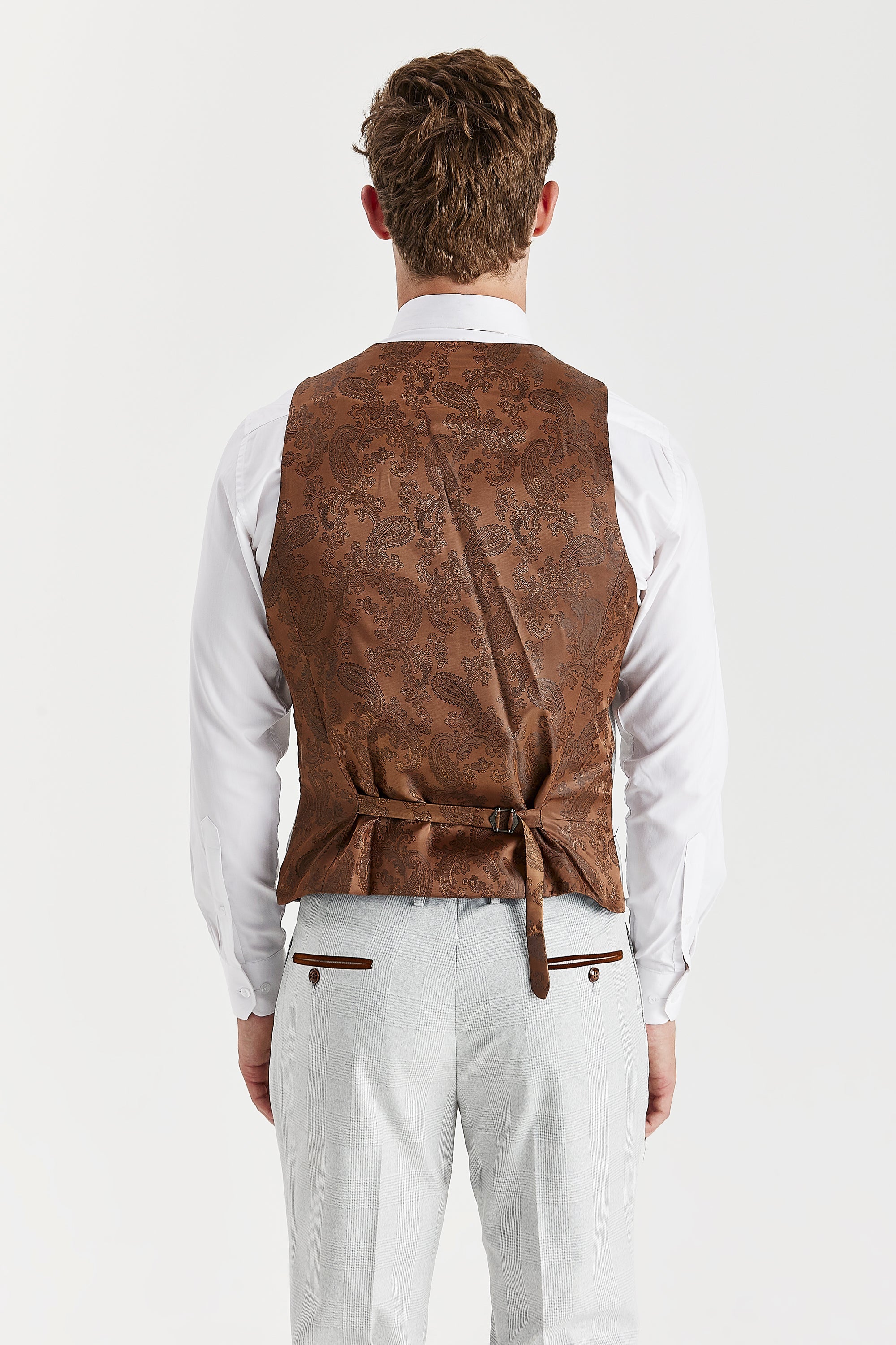Rear view of the stone waistcoat with a brown paisley back panel and adjustable strap, worn with a white shirt and matching trousers.