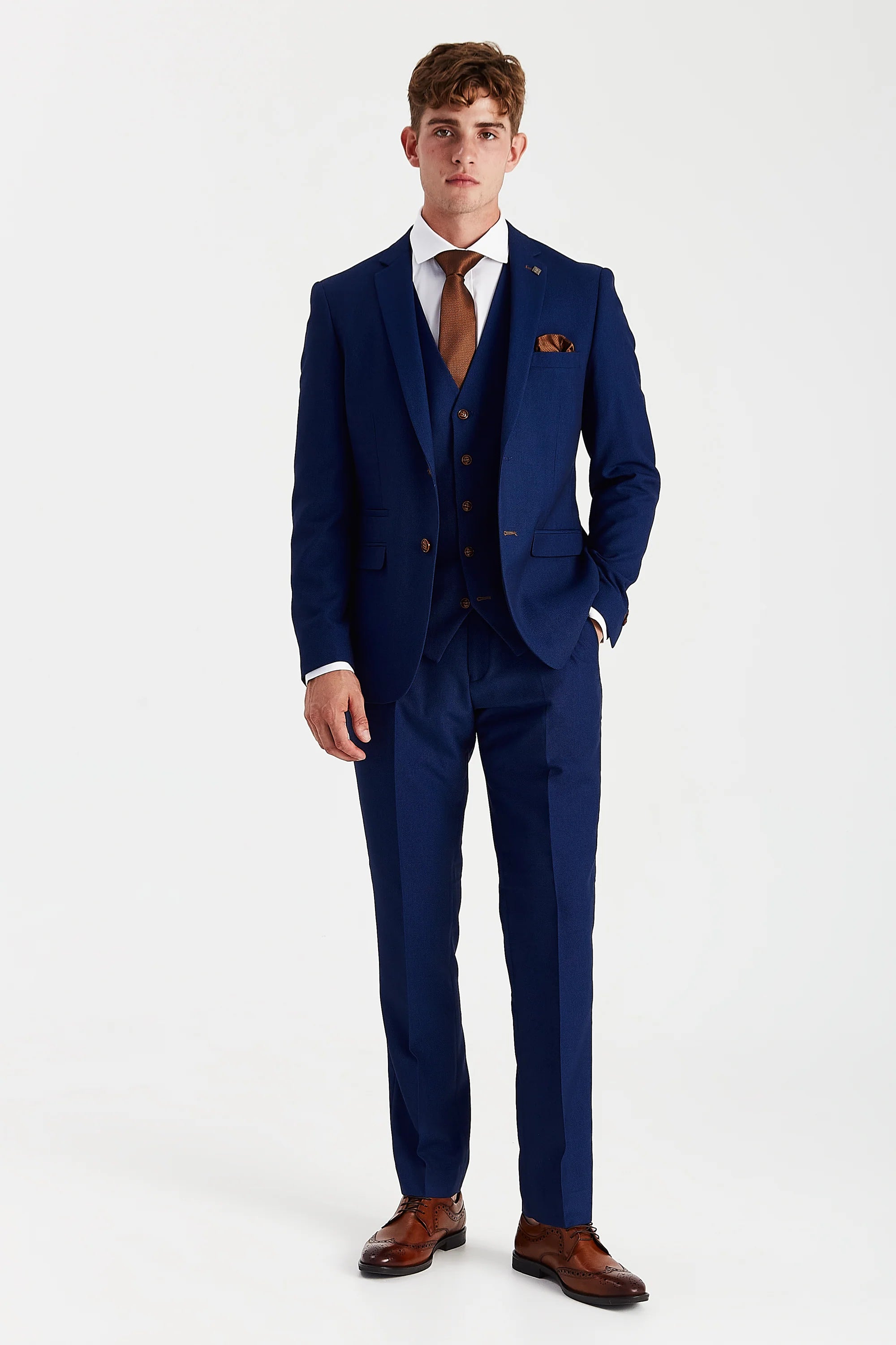 Full-length front view of a man wearing a blue textured three piece suit with a white shirt, brown tie, brown pocket square and brown shoes.