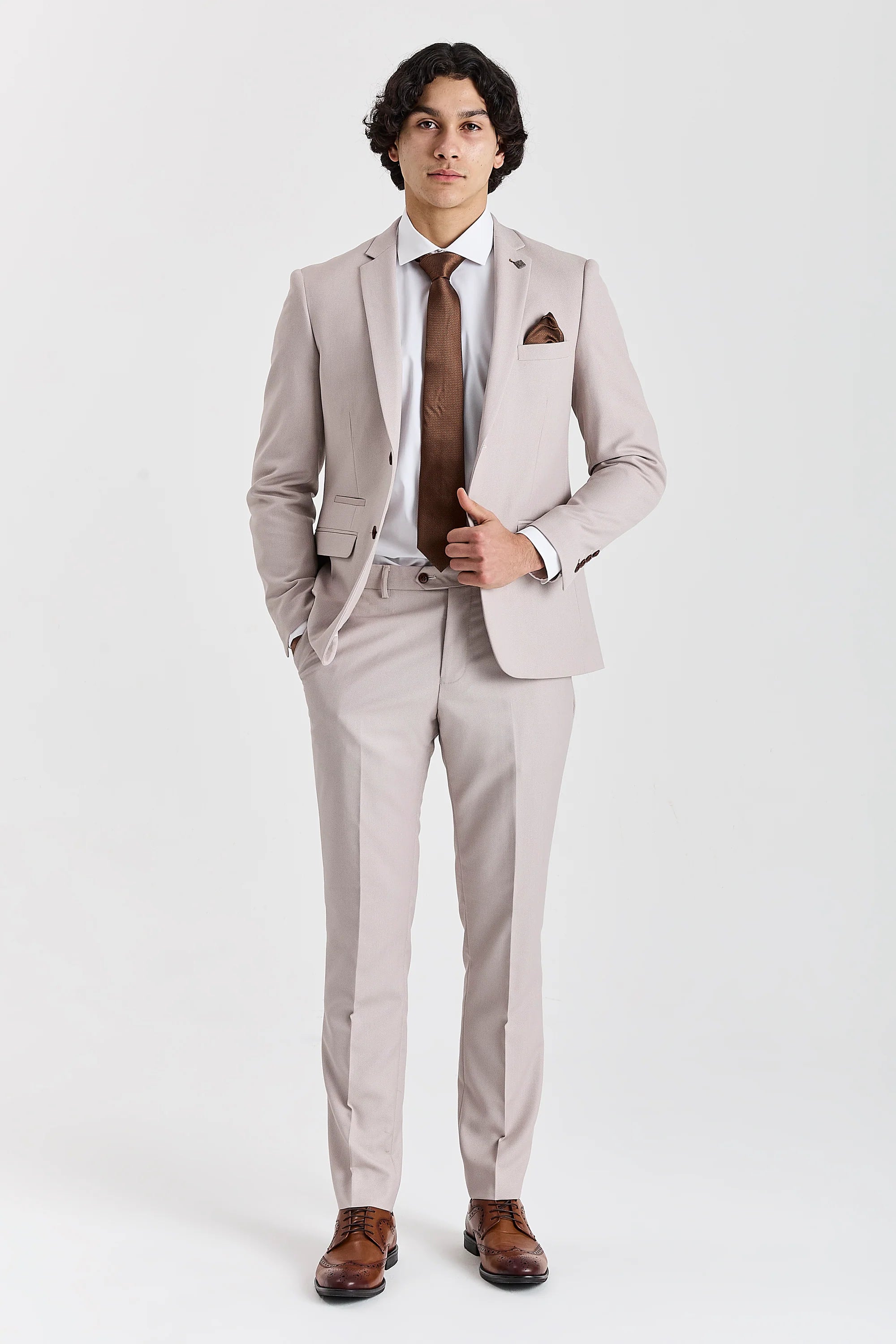 Full front view of stone textured two-piece suit worn with a white shirt, brown tie and brown brogues