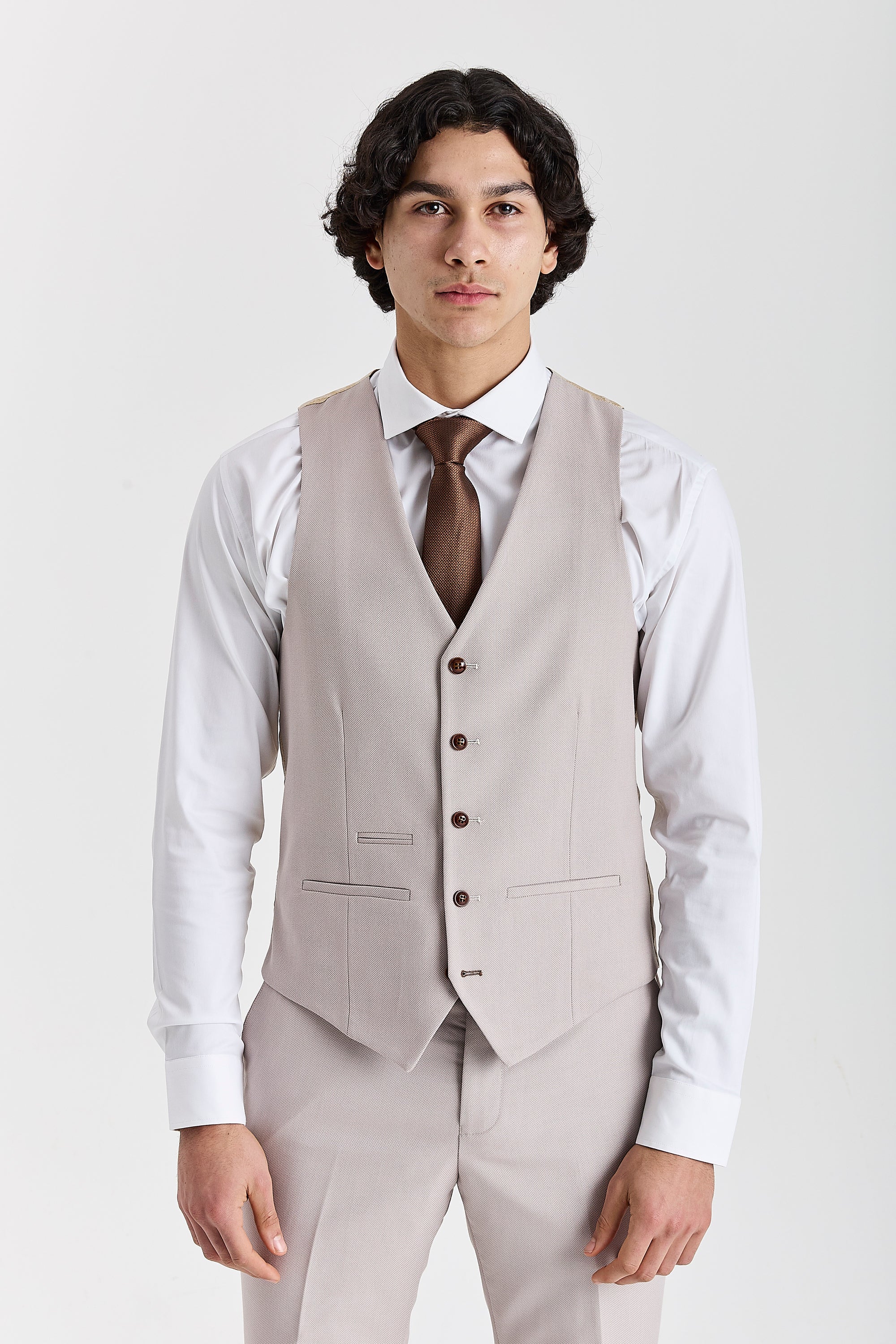 Front view of the stone waistcoat with brown buttons, worn with matching trousers, a white shirt and a brown tie.