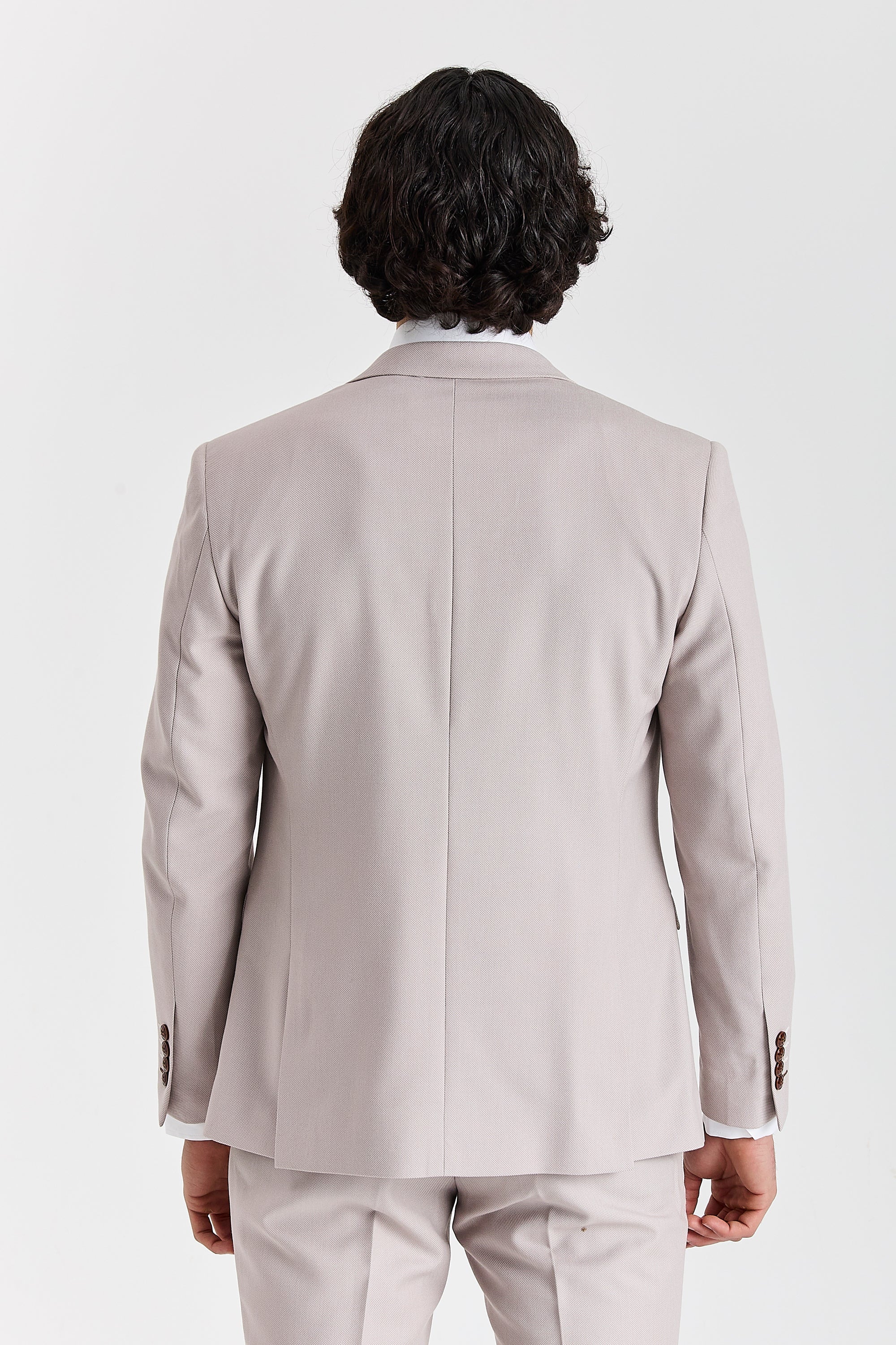 Back view of a stone textured suit jacket with matching trousers and brown sleeve buttons.