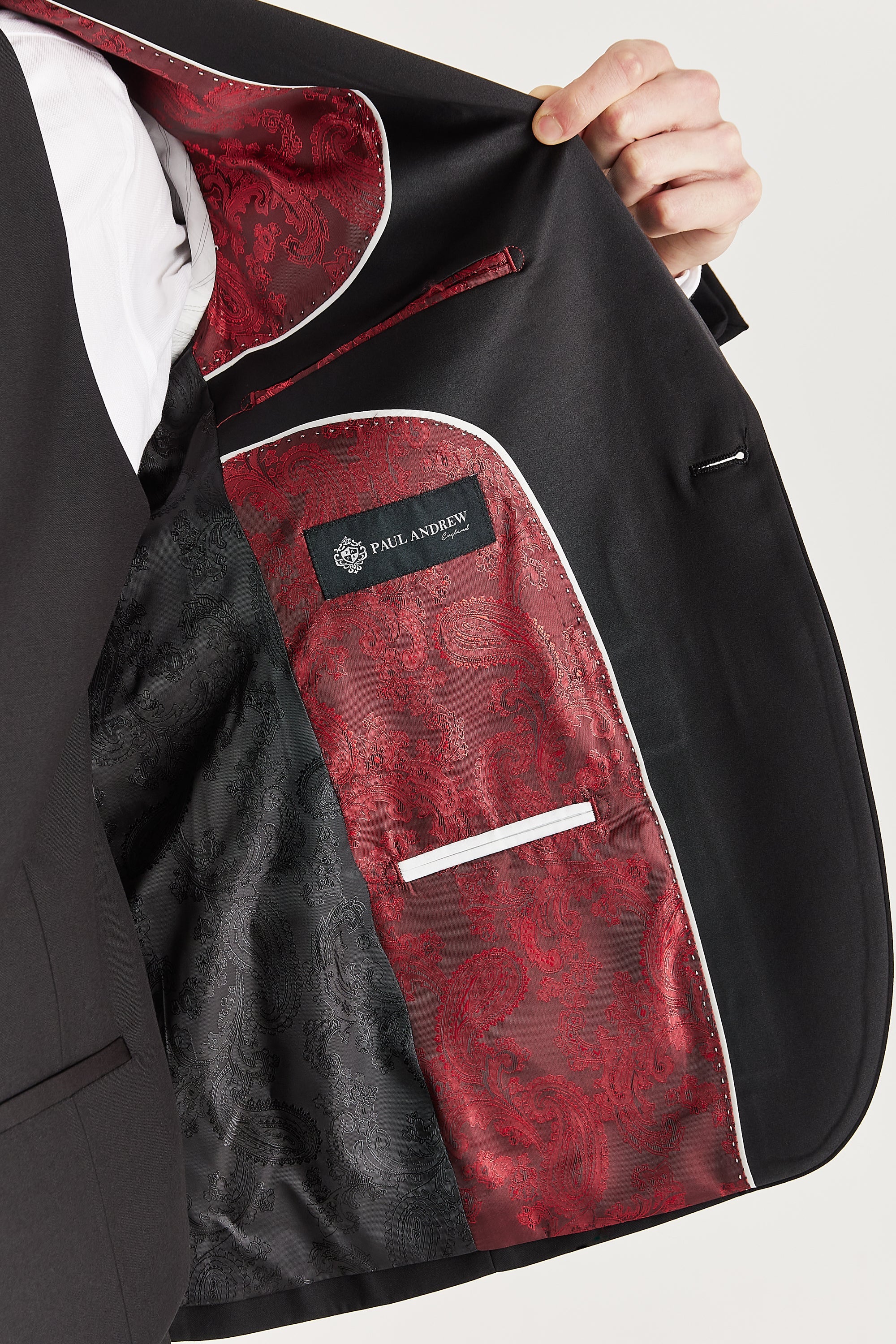 Interior view of the black dinner suit blazer with red and black paisley lining and a visible Paul Andrew logo label stitched inside.