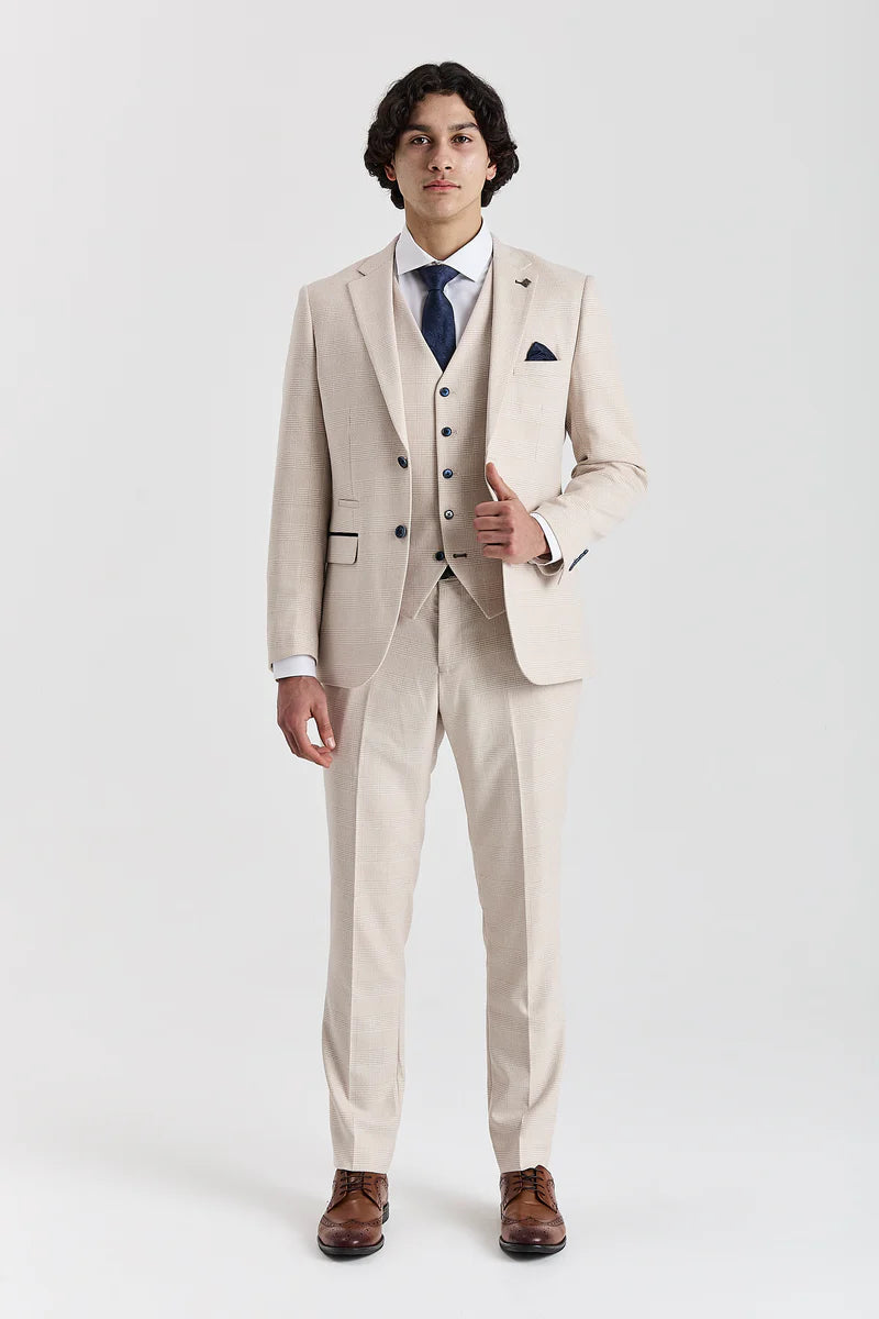 Full front view of a men's cream check three-piece suit comprising a jacket, waistcoat, and trousers, paired with a white shirt, dark blue tie, and brown brogues.