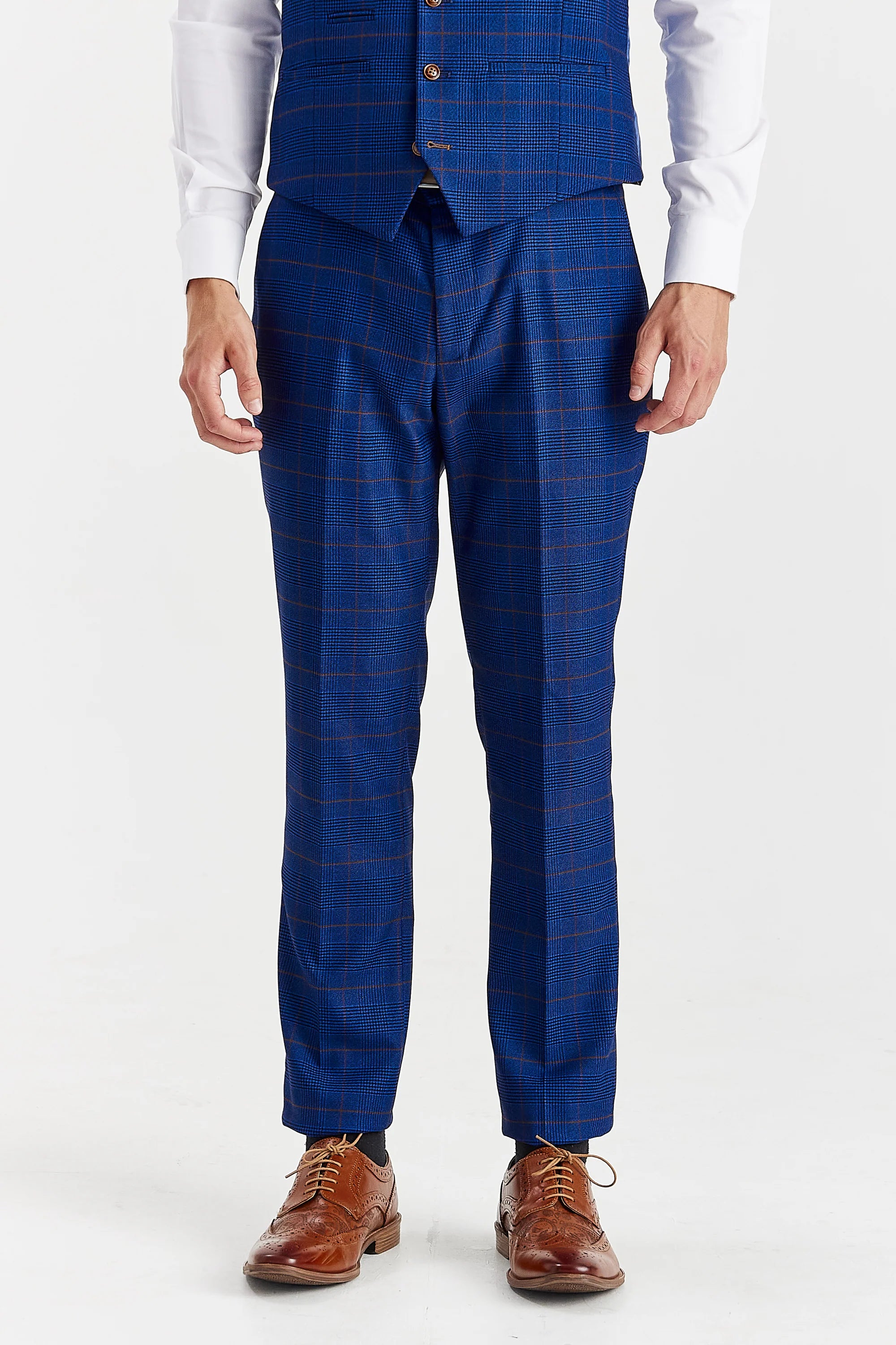 Close-up front view of tailored navy blue glen check suit trousers and a partially visible matching waistcoat, highlighting the slim cut extending down to brown leather brogue shoes.