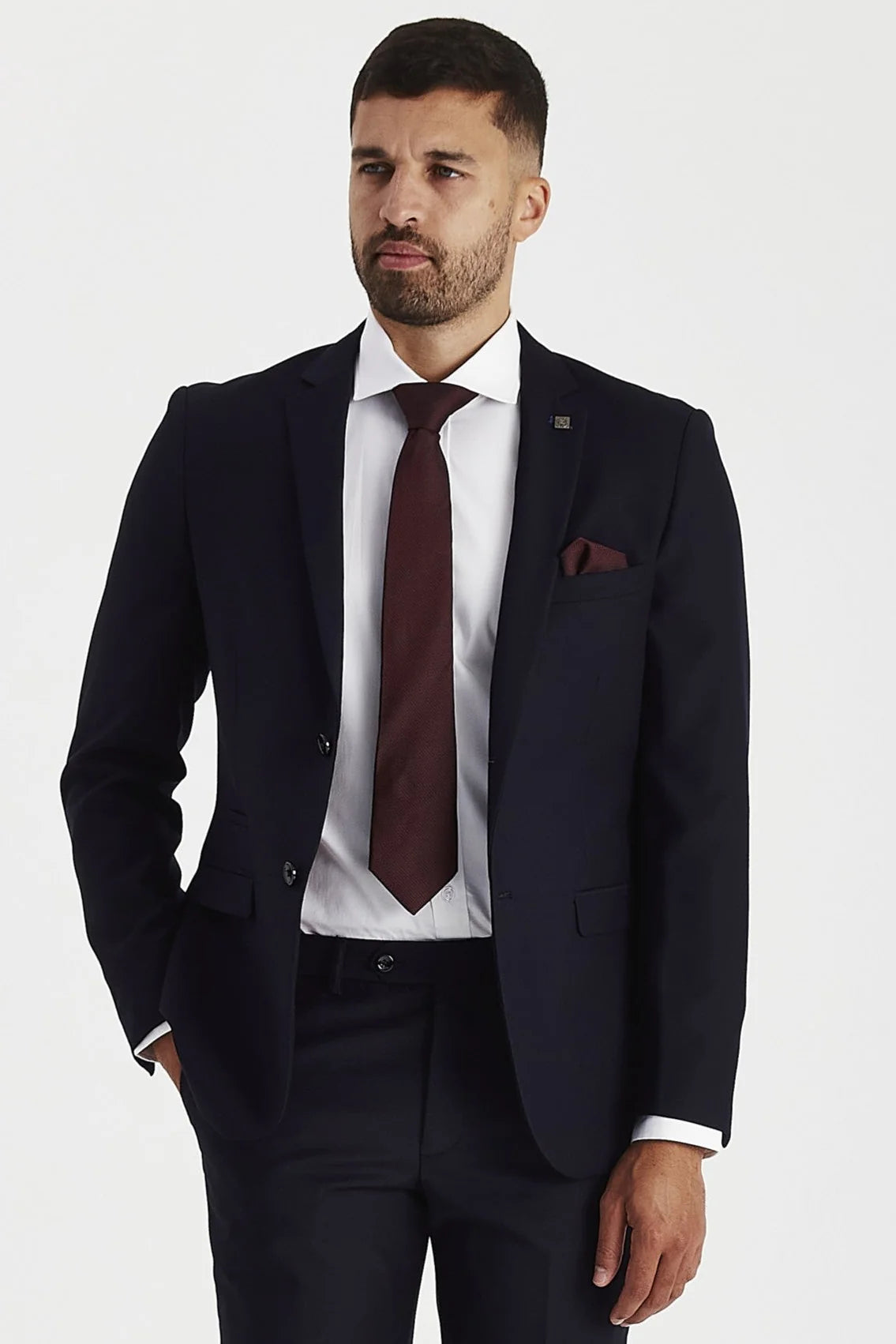 front view of a man wearing a tailored navy suit blazer and trousers, styled with a white shirt, burgundy tie, and matching pocket square.