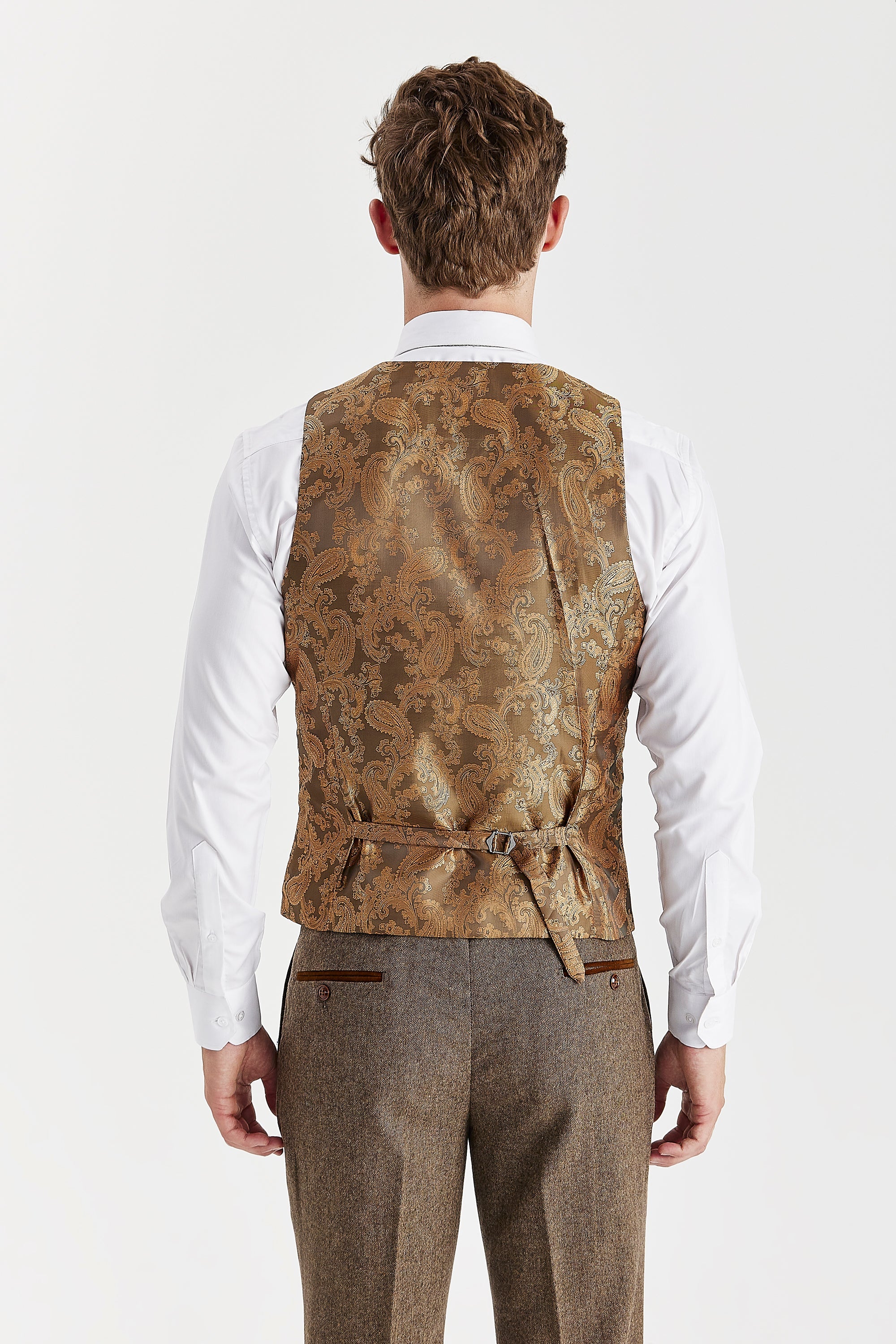 Rear view of the brown waistcoat with a brown paisley back panel and adjustable strap, worn with a white shirt and matching trousers.