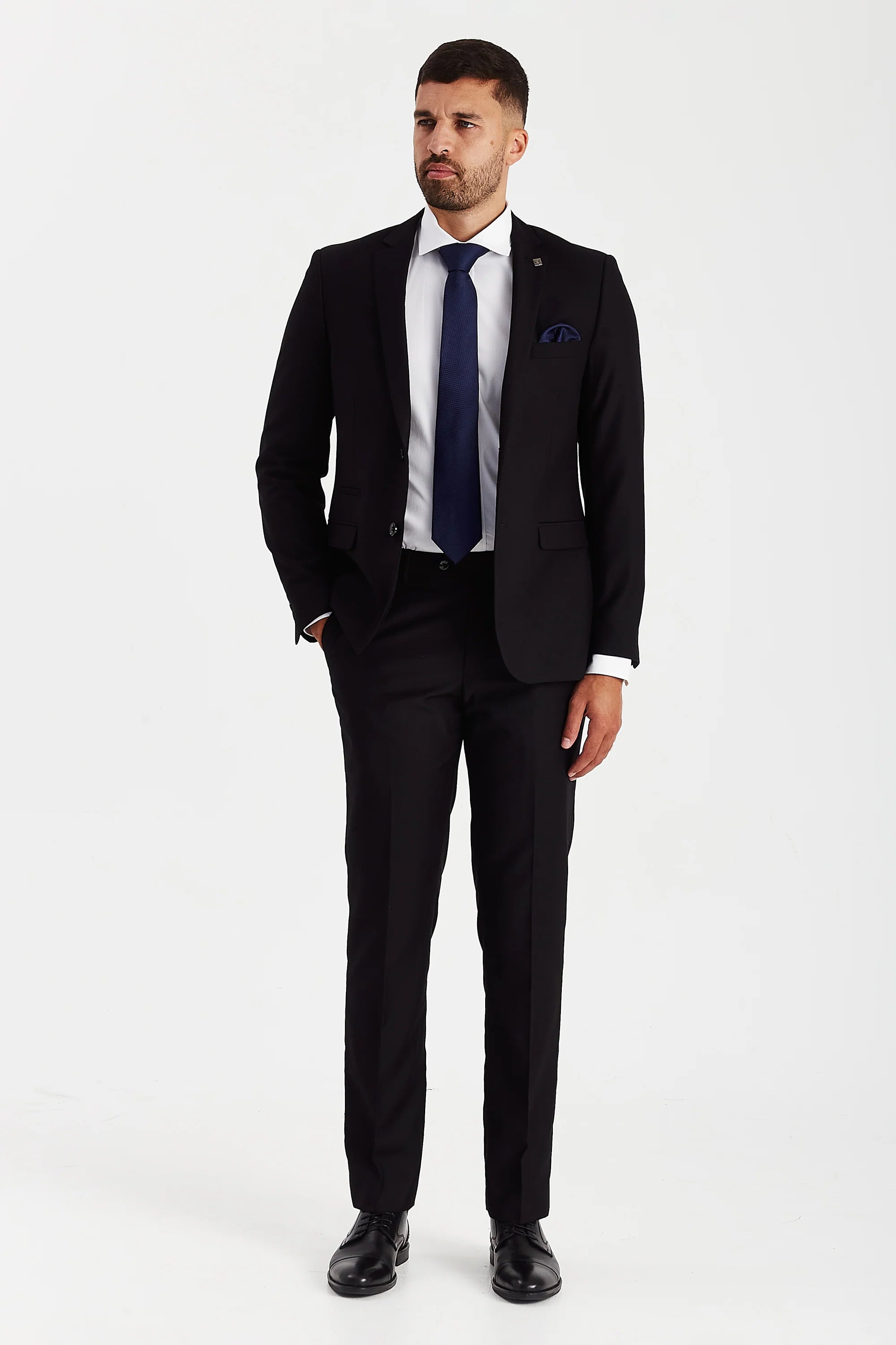Full front view of black two-piece suit worn with a white shirt, navy tie and black dress shoes