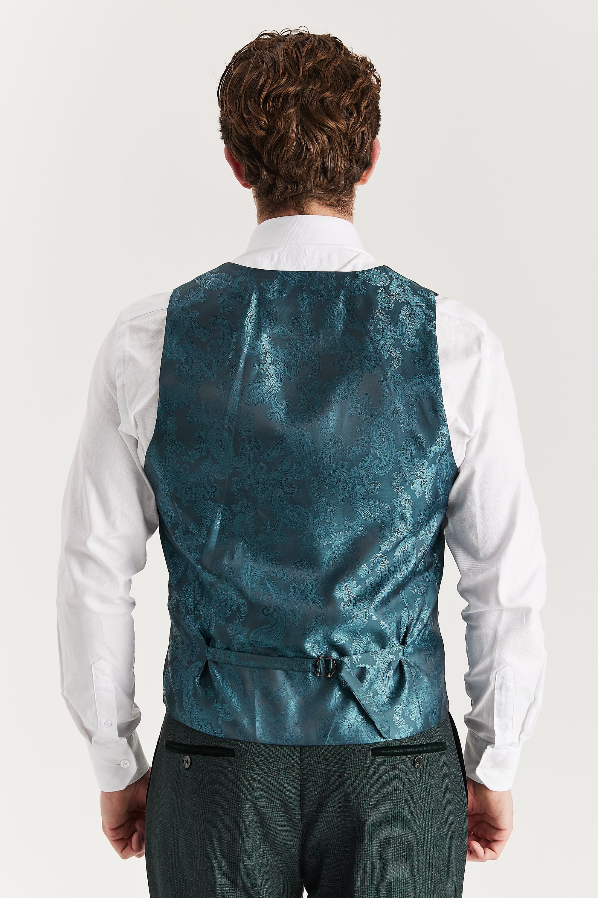 Rear view of the olive waistcoat with a paisley back panel and adjustable strap, worn with a white shirt and matching trousers.