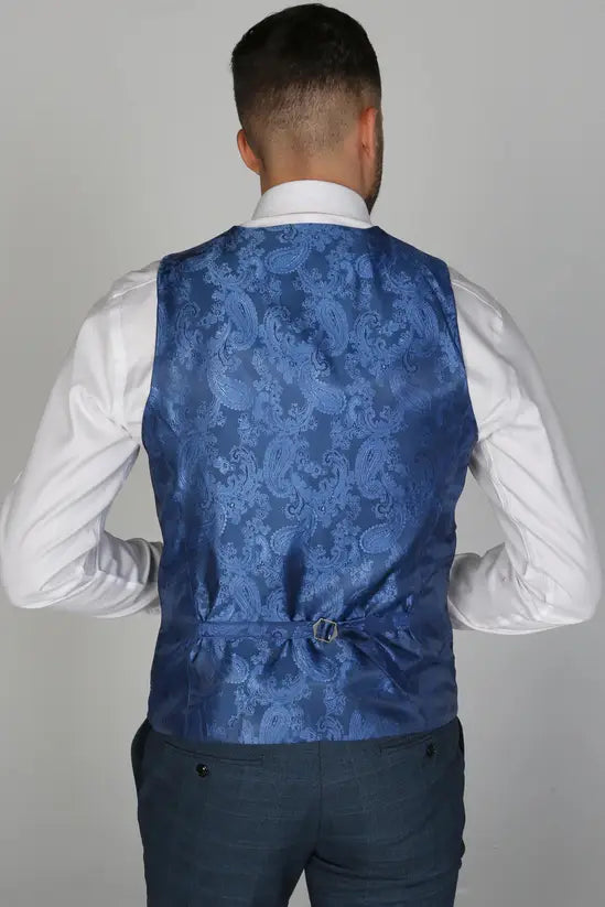 Rear view of the blue waistcoat with a blue paisley back panel and adjustable strap, worn with a white shirt and blue trousers.