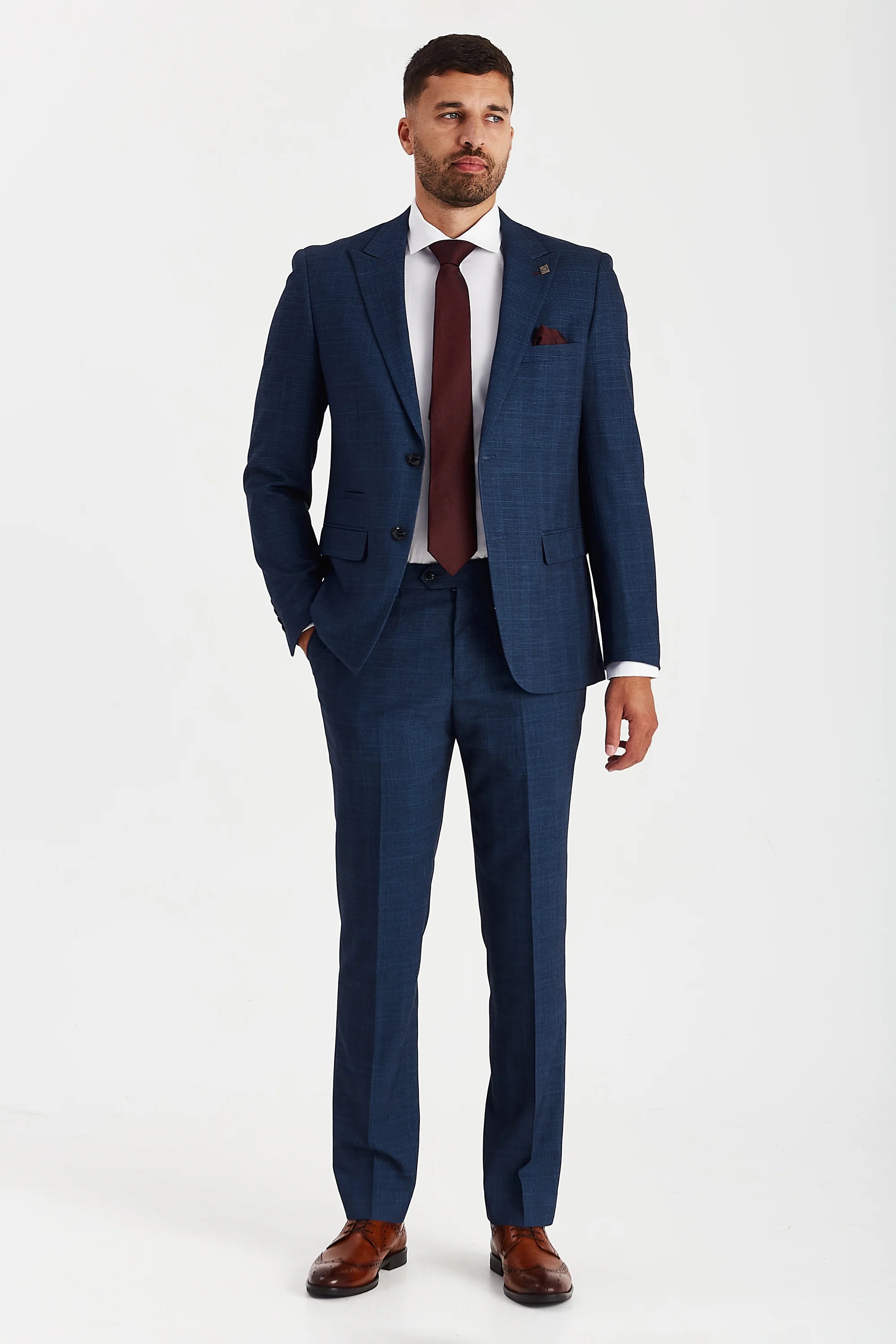 Full body view of a model wearing the Viceroy Navy Men's Two Piece Suit. The tailored outfit consists of a matching blazer and trousers in deep navy fabric with a refined check pattern, paired with a white shirt, burgundy tie, and brown leather shoes.