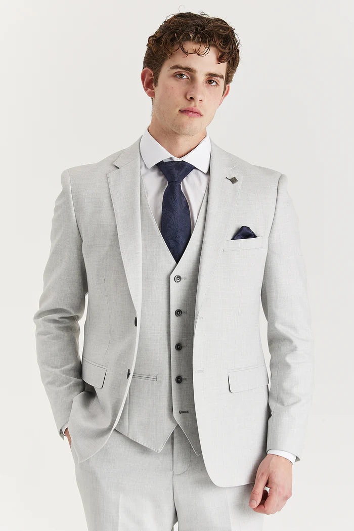 Close-up of a model wearing a silver three-piece suit with a navy tie and pocket square, highlighting the structured fit and details.