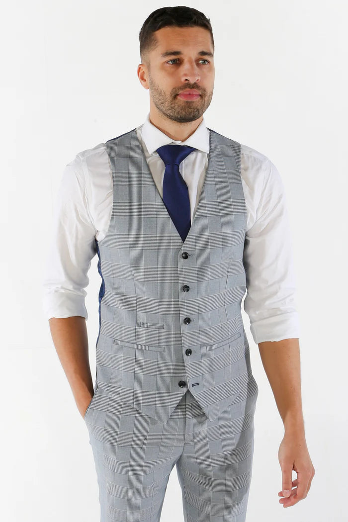 Model in a sky blue check waistcoat and navy tie, sleeves rolled up, showing front tailoring detail.