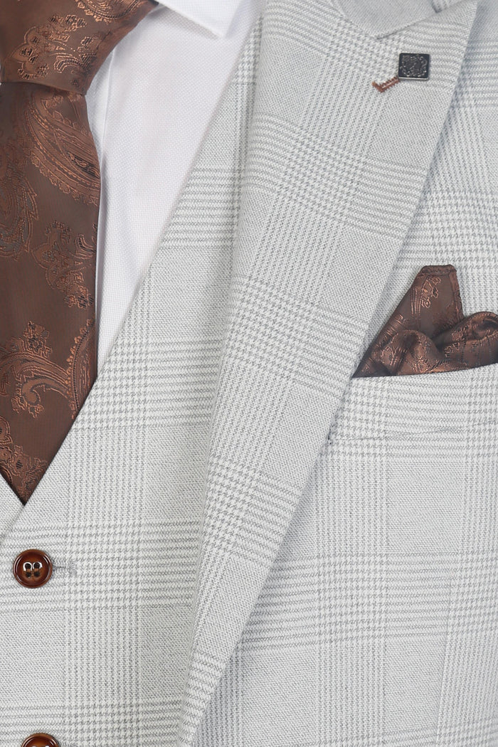 Close-up of the suit’s lapel, brown paisley tie, and pocket square, highlighting the stone check fabric and contrast detailing.