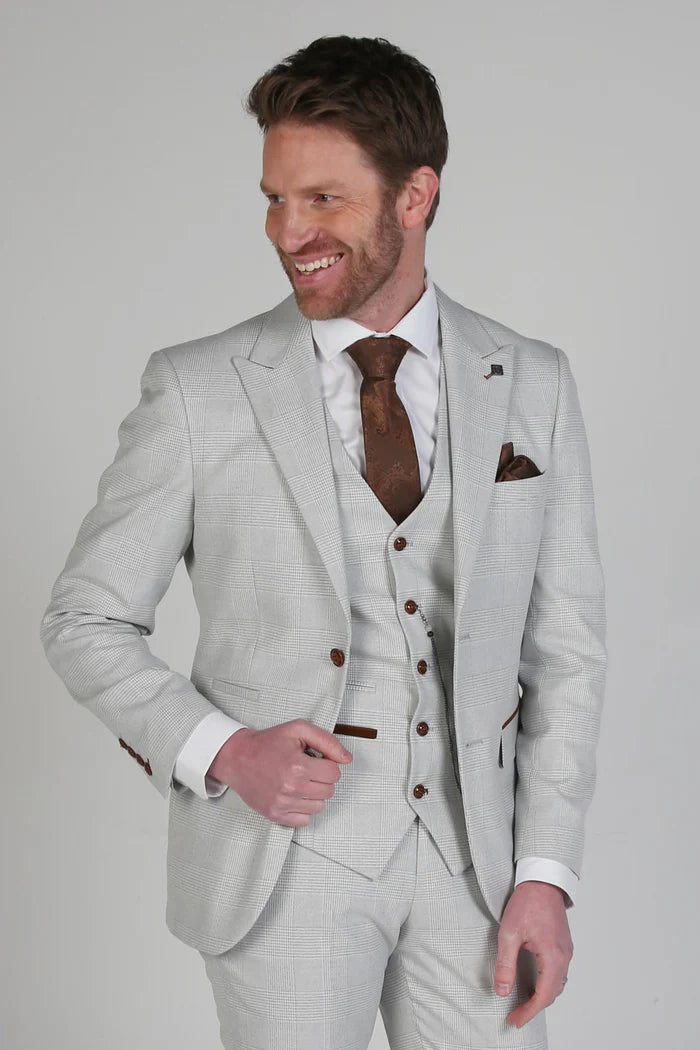 Man smiling while wearing a stone check three-piece suit with a brown paisley tie and matching pocket square, shown from the waist up.